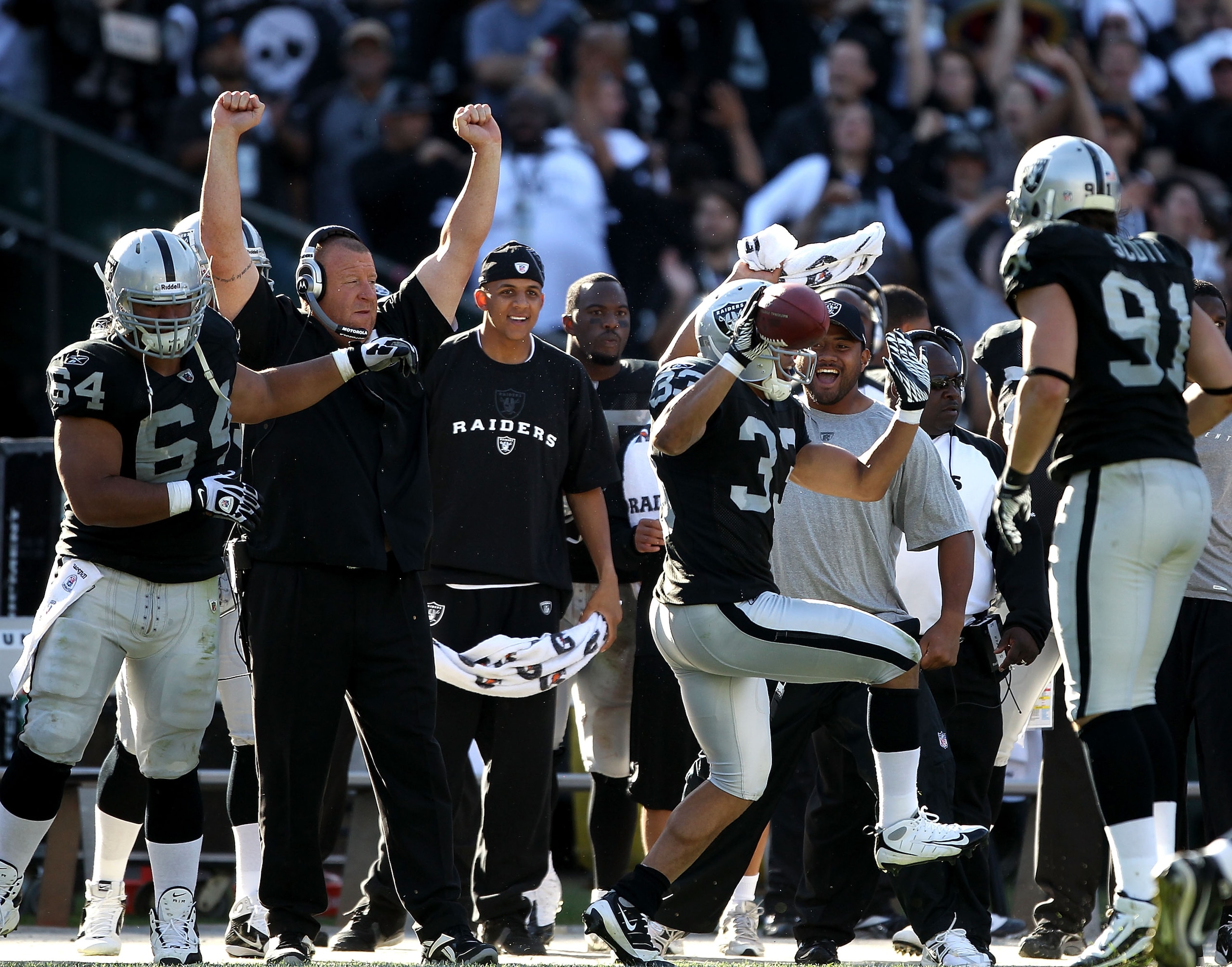 OAKLAND, CA - OCTOBER 31: Head coach Tom Cable of the Oakland Raiders celebrates with his arms in the air while Tyvon Branch #33 runs back an interception against the Seattle Seahawks at Oakland-Alameda County Coliseum on October 31, 2010 in Oakland, Cali