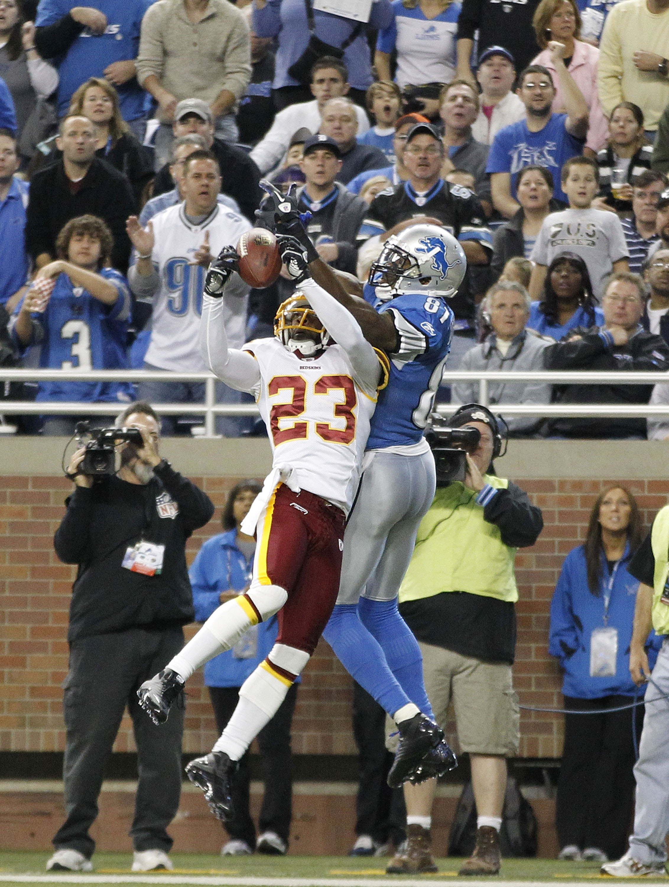 DETROIT - OCTOBER 31:  DeAngelo Hall #23 of the Washingon Redskins intercepts the pass during the second quarter as Calvin Johnson #81 of the Detroit Lions atempts to defend during the game at Ford Field on October 31, 2010 in Detroit, Michigan.  (Photo b