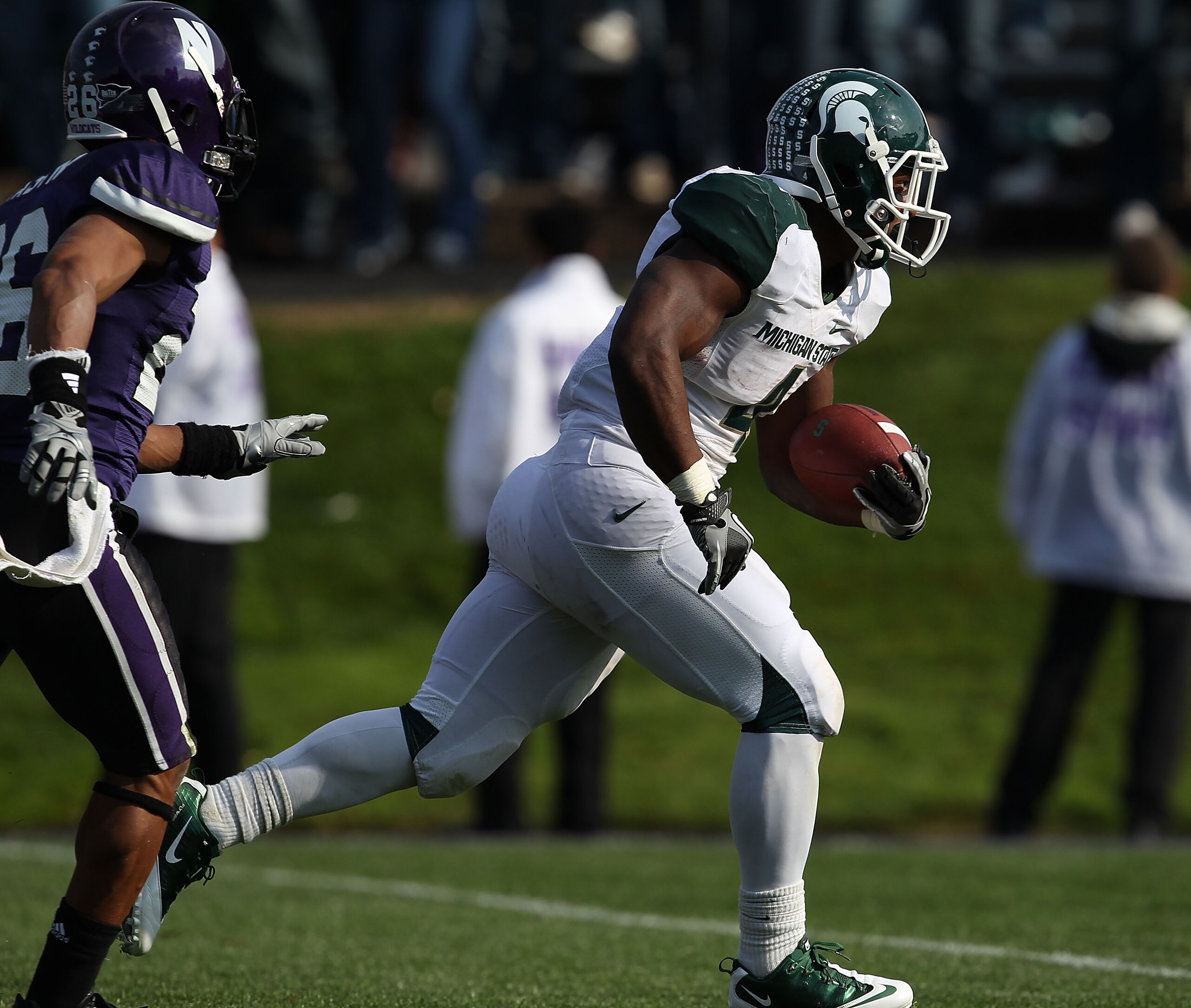 EVANSTON, IL - OCTOBER 23: Edwin Baker #4 of the Michigan State Spartans breaks away from Jordan Mabin #26 of the Northwestern Wildcats as he runs for a touchdown late in the 4th quarter at Ryan Field on October 23, 2010 in Evanston, Illinois. Michigan St