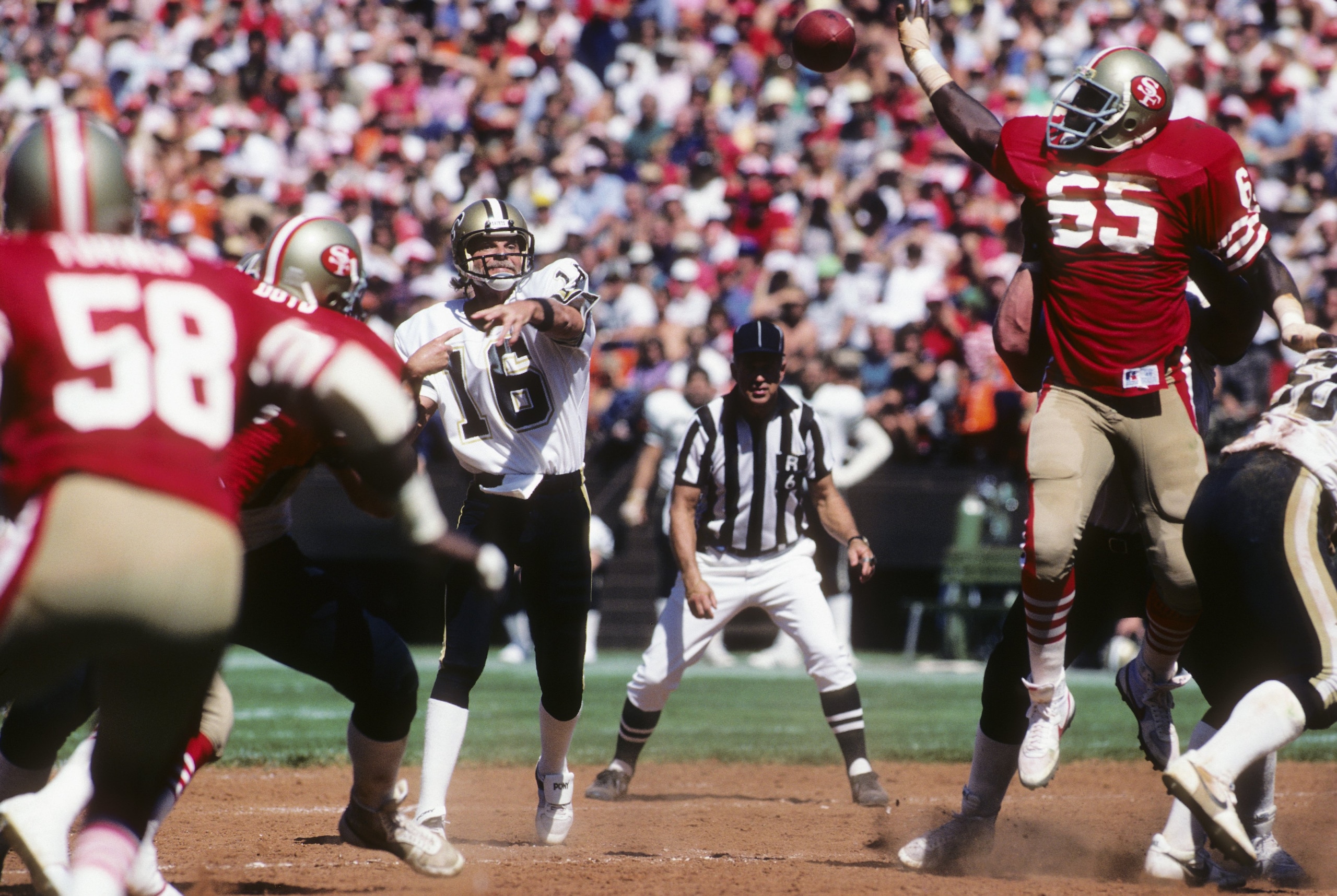 SAN FRANCISCO - SEPTEMBER 16: Defenive end Lawrence Pillers #65 of the San Francisco 49ers attempts to bat down a pass thrown by quarterback Ken Stabler #16 of the New Orleans Saints as NFL referee Tom Dooley #6 watches the action during a game at Candle SAN FRANCISCO - SEPTEMBER 16: Defenive end Lawrence Pillers #65 of the San Francisco 49ers attempts to bat down a pass thrown by quarterback Ken Stabler #16 of the New Orleans Saints as NFL referee Tom Dooley #6 watches the action during a game at Candle