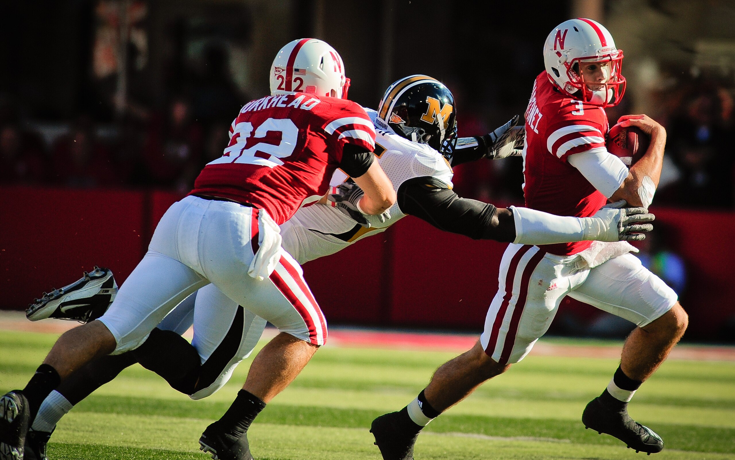 LINCOLN, NE - OCTOBER 30: Quarterback Taylor Martinez #3 of the Nebraska Cornhuskers runs from defensive end Aldon Smith #85 of the Missouri Tigers with help from  running back Rex Burkhead #22 during second half action of their game at Memorial Stadium o