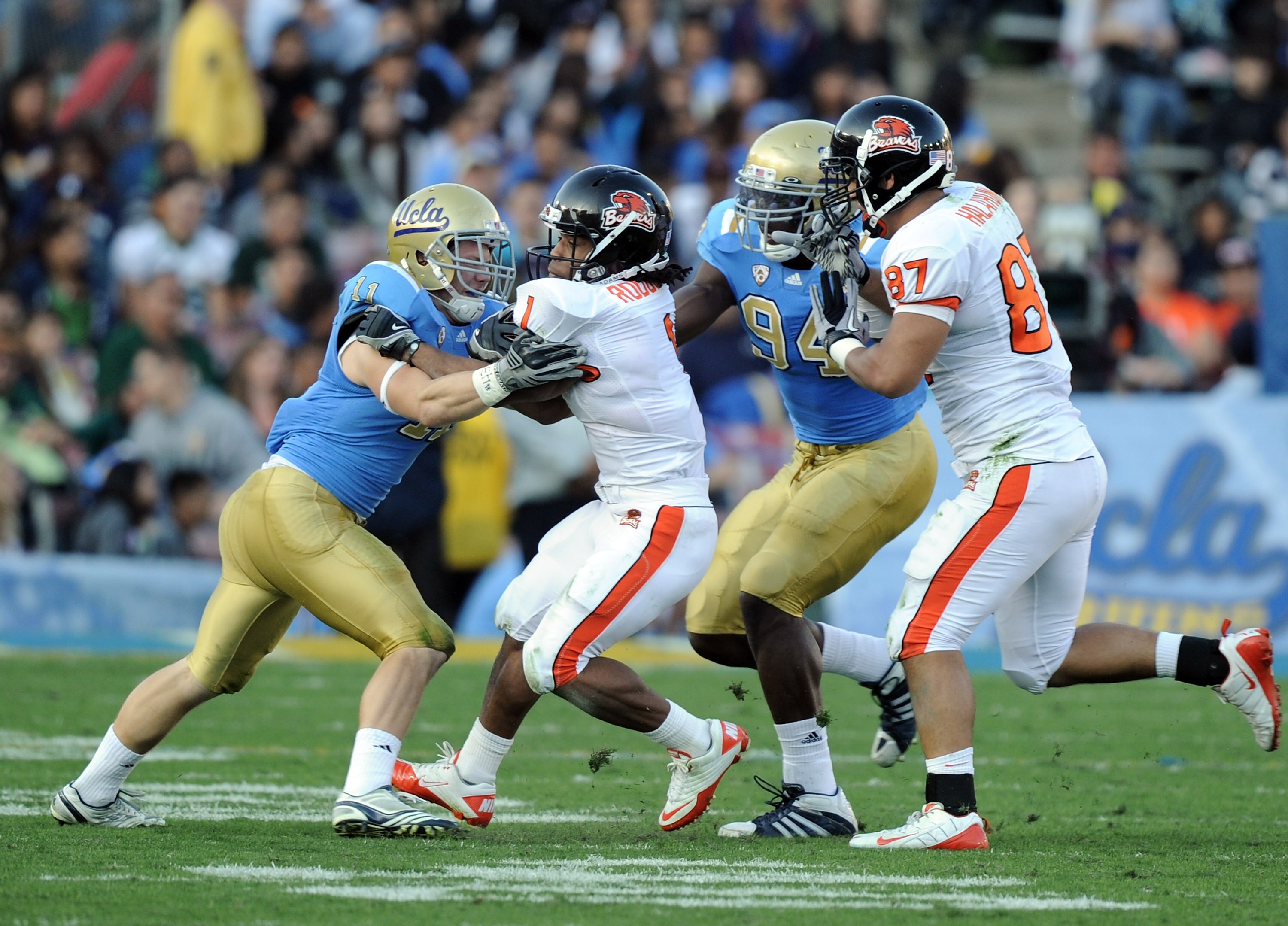 PASADENA, CA - NOVEMBER 06:  Jacquizz Rodgers #1 of the Oregon State Beavers runs between Sean Westgate #11 and Owamagbe Odighizuwa #94 of the UCLA Bruins as Joe Halahuni #87 attempts to block at the Rose Bowl on November 6, 2010 in Pasadena, California.