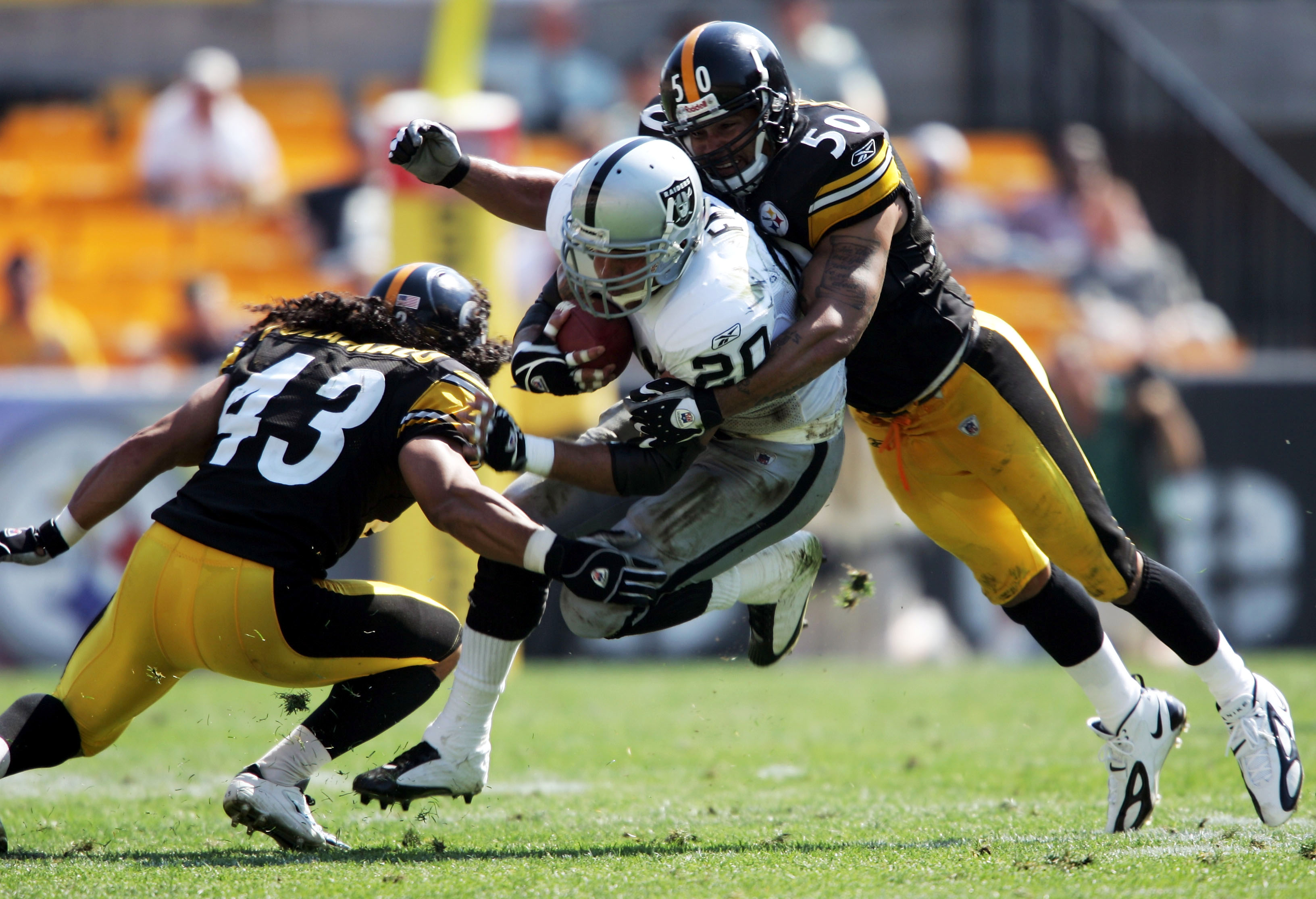 PITTSBURGH - SEPTEMBER 12:  Justin Fargas #20 of the Oakland Raiders runs with the ball while tackled by  Troy Polamalu #43 and Larry Foote #50 of the Pittsburgh Steelers on September 12, 2004 at Heinz Field in Pittsburgh, Pennsylvania. The Steelers won 2