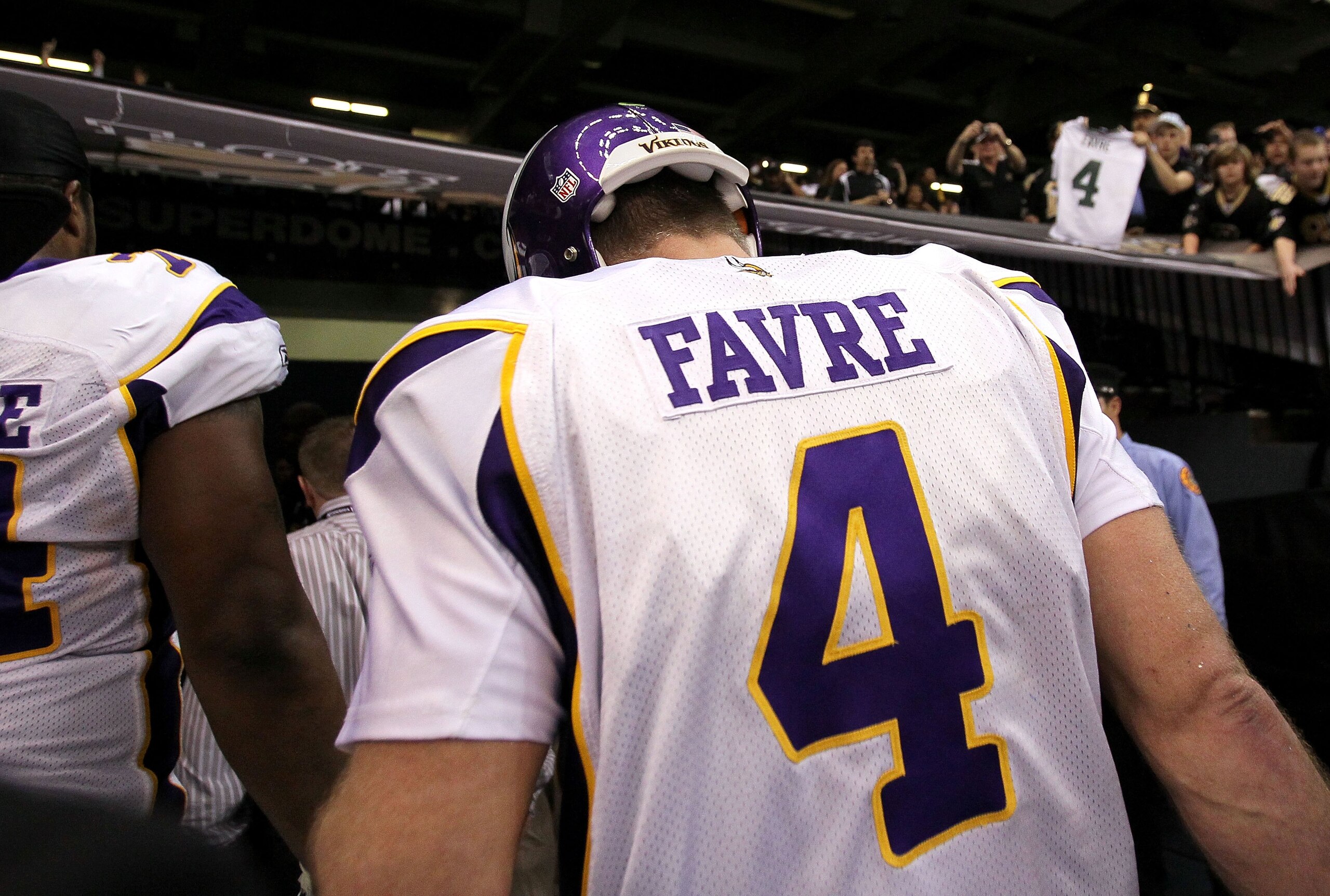 NEW ORLEANS - JANUARY 24:  A fan in the stands holds up a Green Bay Packers #4 jersey as Brett Favre #4 of the Minnesota Vikings walks off the field after the Vikings lost to the New Orleans Saints 31-28 in overtime during the NFC Championship Game at the