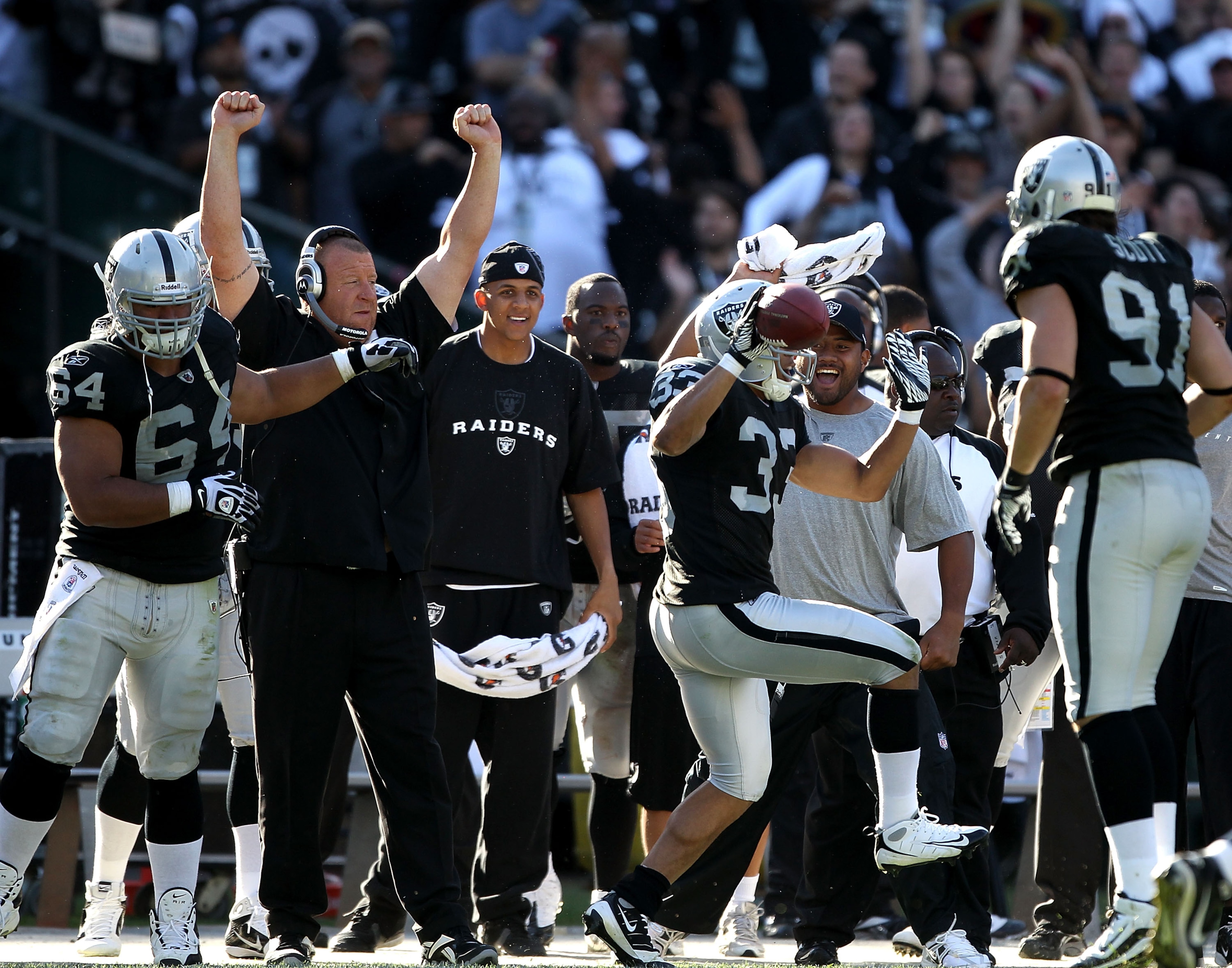 OAKLAND, CA - OCTOBER 31: Head coach Tom Cable of the Oakland Raiders celebrates with his arms in the air while Tyvon Branch #33 runs back an interception against the Seattle Seahawks at Oakland-Alameda County Coliseum on October 31, 2010 in Oakland, Cali