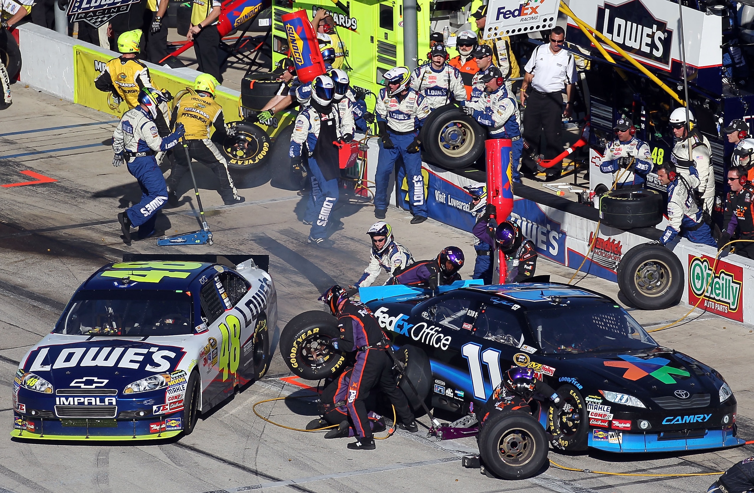 FORT WORTH, TX - NOVEMBER 07: Jimmie Johnson, driver of the #48 Lowe's Chevrolet, pulls out of his pit as Denny Hamlin, driver of the #11 FedEx Office Toyota, makes a pit stop during the NASCAR Sprint Cup Series AAA Texas 500 at Texas Motor Speedway on N FORT WORTH, TX - NOVEMBER 07: Jimmie Johnson, driver of the #48 Lowe's Chevrolet, pulls out of his pit as Denny Hamlin, driver of the #11 FedEx Office Toyota, makes a pit stop during the NASCAR Sprint Cup Series AAA Texas 500 at Texas Motor Speedway on N