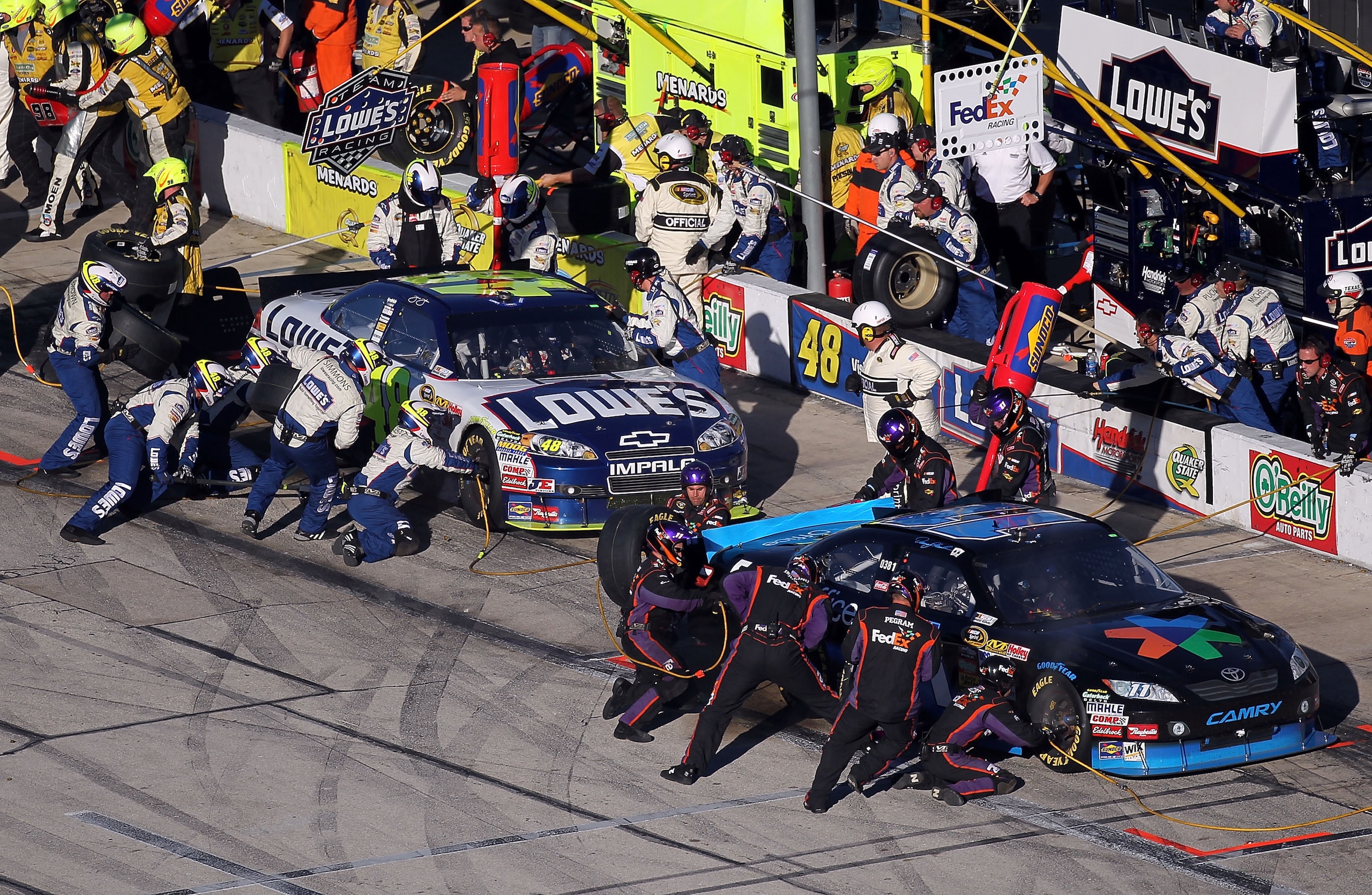 FORT WORTH, TX - NOVEMBER 07: Jimmie Johnson, driver of the #48 Lowe's Chevrolet, and Denny Hamlin, driver of the #11 FedEx Office Toyota, make pit stops during the NASCAR Sprint Cup Series AAA Texas 500 at Texas Motor Speedway on November 7, 2010 in For FORT WORTH, TX - NOVEMBER 07: Jimmie Johnson, driver of the #48 Lowe's Chevrolet, and Denny Hamlin, driver of the #11 FedEx Office Toyota, make pit stops during the NASCAR Sprint Cup Series AAA Texas 500 at Texas Motor Speedway on November 7, 2010 in For