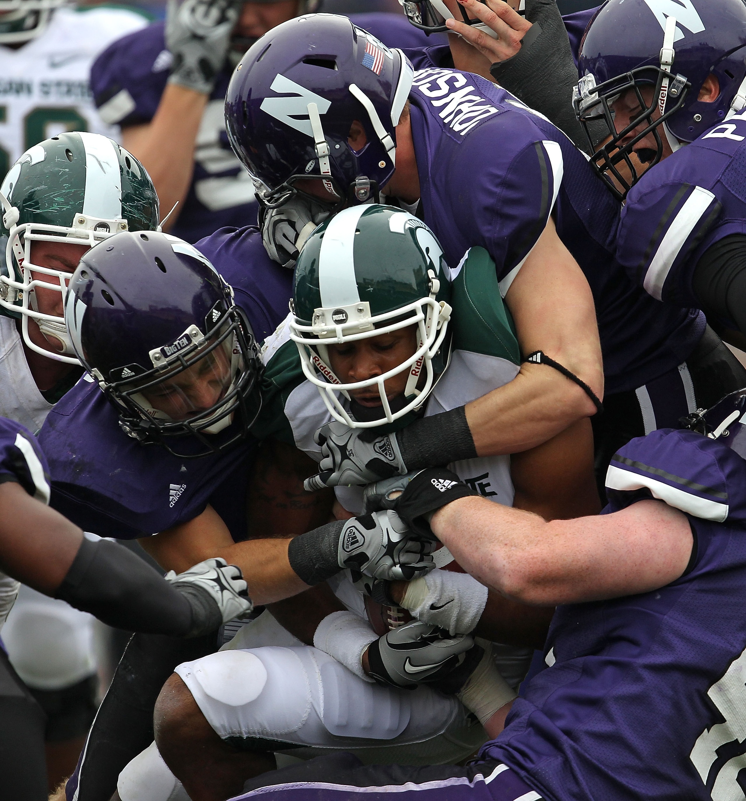 EVANSTON, IL - OCTOBER 23: B.J. Cunningham #3 of the Michigan State Spartans is stopped by (L-R) Hunter Bates #7, Ben Johnson #35 and Kevin Watt #42 of the Northwestern Wildcats at Ryan Field on October 23, 2010 in Evanston, Illinois. Michigan State defea EVANSTON, IL - OCTOBER 23: B.J. Cunningham #3 of the Michigan State Spartans is stopped by (L-R) Hunter Bates #7, Ben Johnson #35 and Kevin Watt #42 of the Northwestern Wildcats at Ryan Field on October 23, 2010 in Evanston, Illinois. Michigan State defea