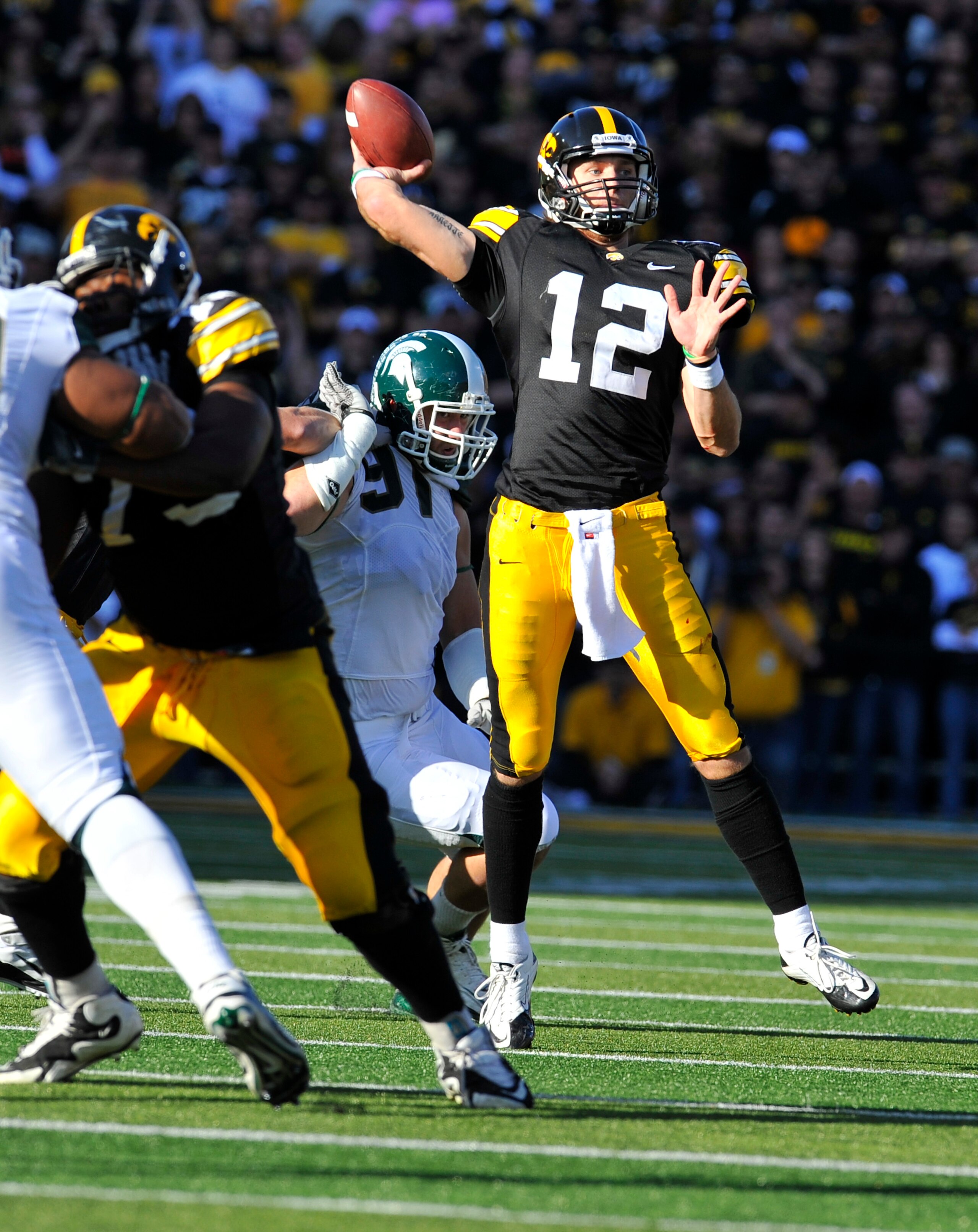 IOWA CITY, IA - OCTOBER 30: Quarterback Ricky Stanzi #12 of the University of Iowa Hawkeyes throw under pressure from defensive end Tyler Hoover #91 of the Michigan State Spartans during the first half of play at Kinnick Stadium on October 30, 2010 in Iow