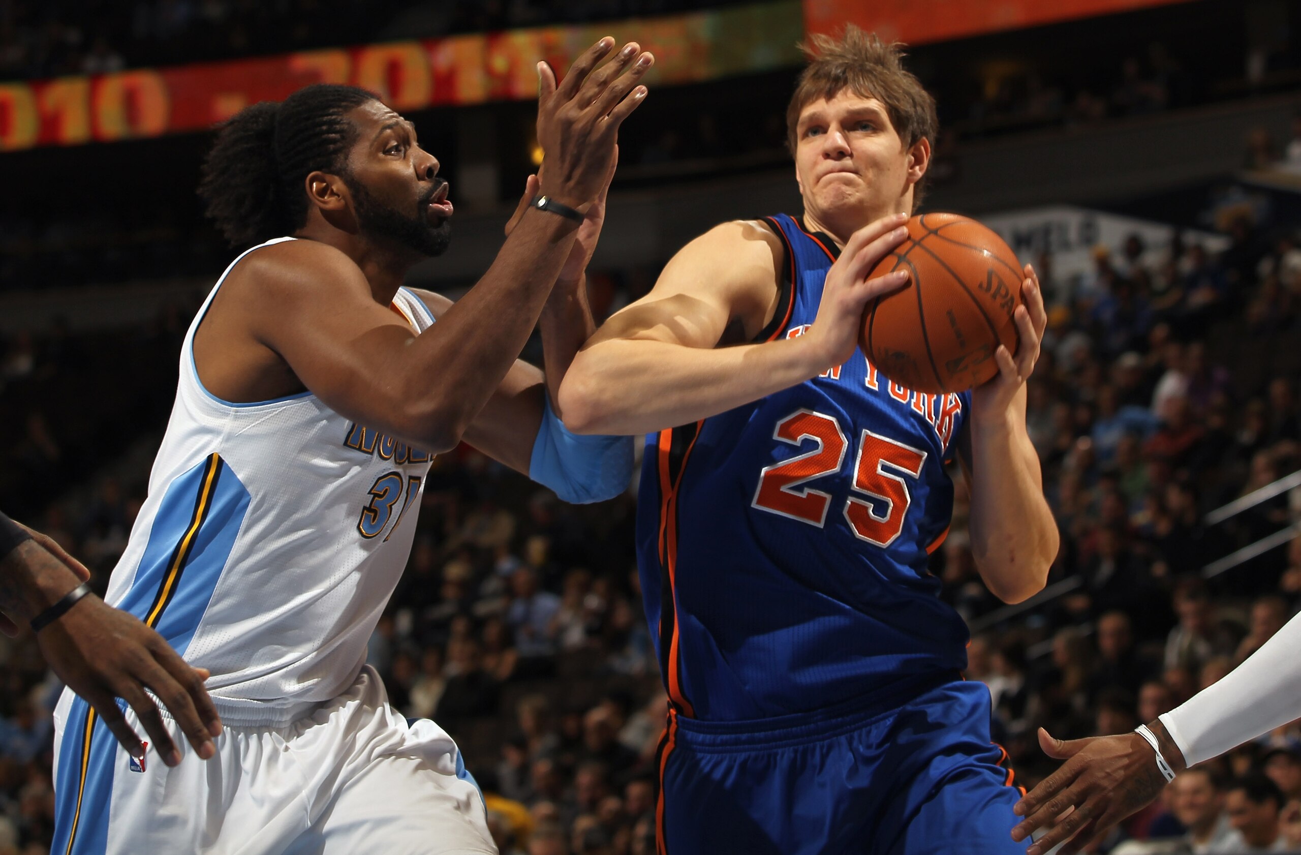 DENVER - NOVEMBER 16:  Timofey Mozgov #25 of the New York Knicks drives past Nene #31 of the Denver Nuggets at the Pepsi Center on November 16, 2010 in Denver, Colorado. NOTE TO USER: User expressly acknowledges and agrees that, by downloading and/or usin