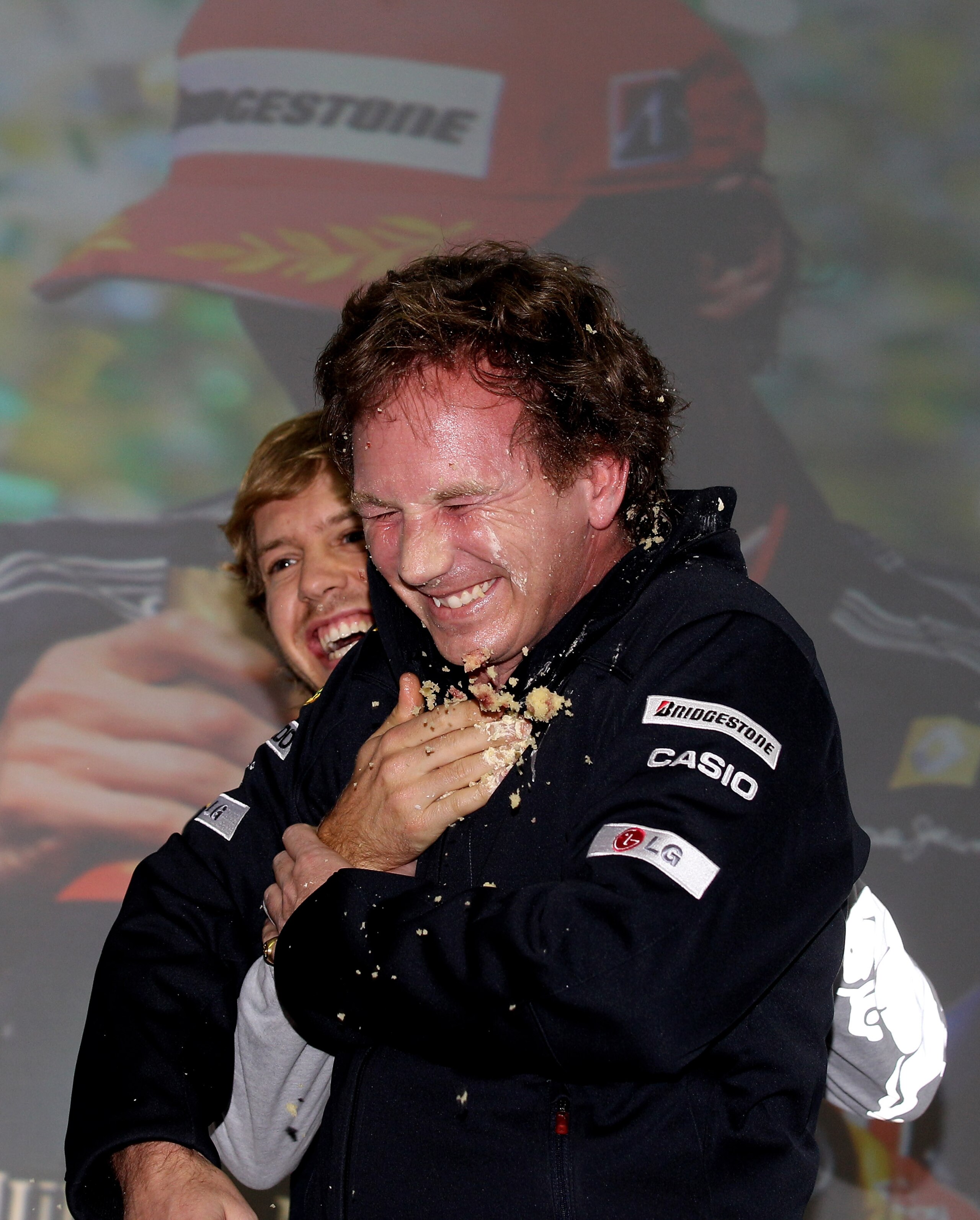 MILTON KEYNES, ENGLAND - NOVEMBER 16:  New Formula 1 World Champion Sebastian Vettel and team mate Mark Webber throw birthday cake over team principal Christian Horner at Red Bull headquaters in Milton Keynes on November 16, 2010 in Milton Keynes, England
