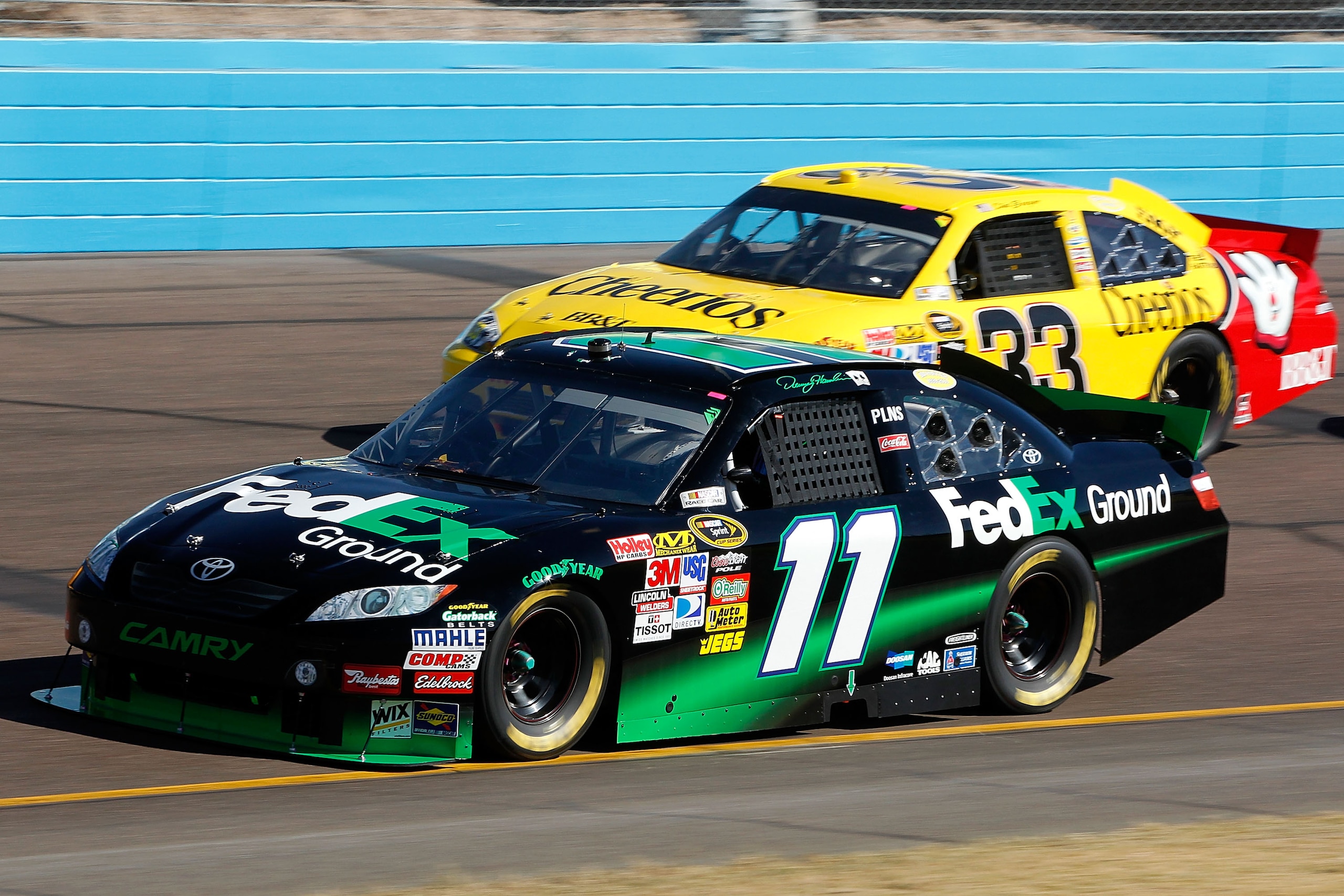 AVONDALE, AZ - NOVEMBER 14:  Denny Hamlin, driver of the #11 FedEx Toyota, leads Clint Bowyer, driver of the #33 Cheerios Chevrolet, during the NASCAR Sprint Cup Series Kobalt Tools 500 at Phoenix International Raceway on November 14, 2010 in Avondale, Ar