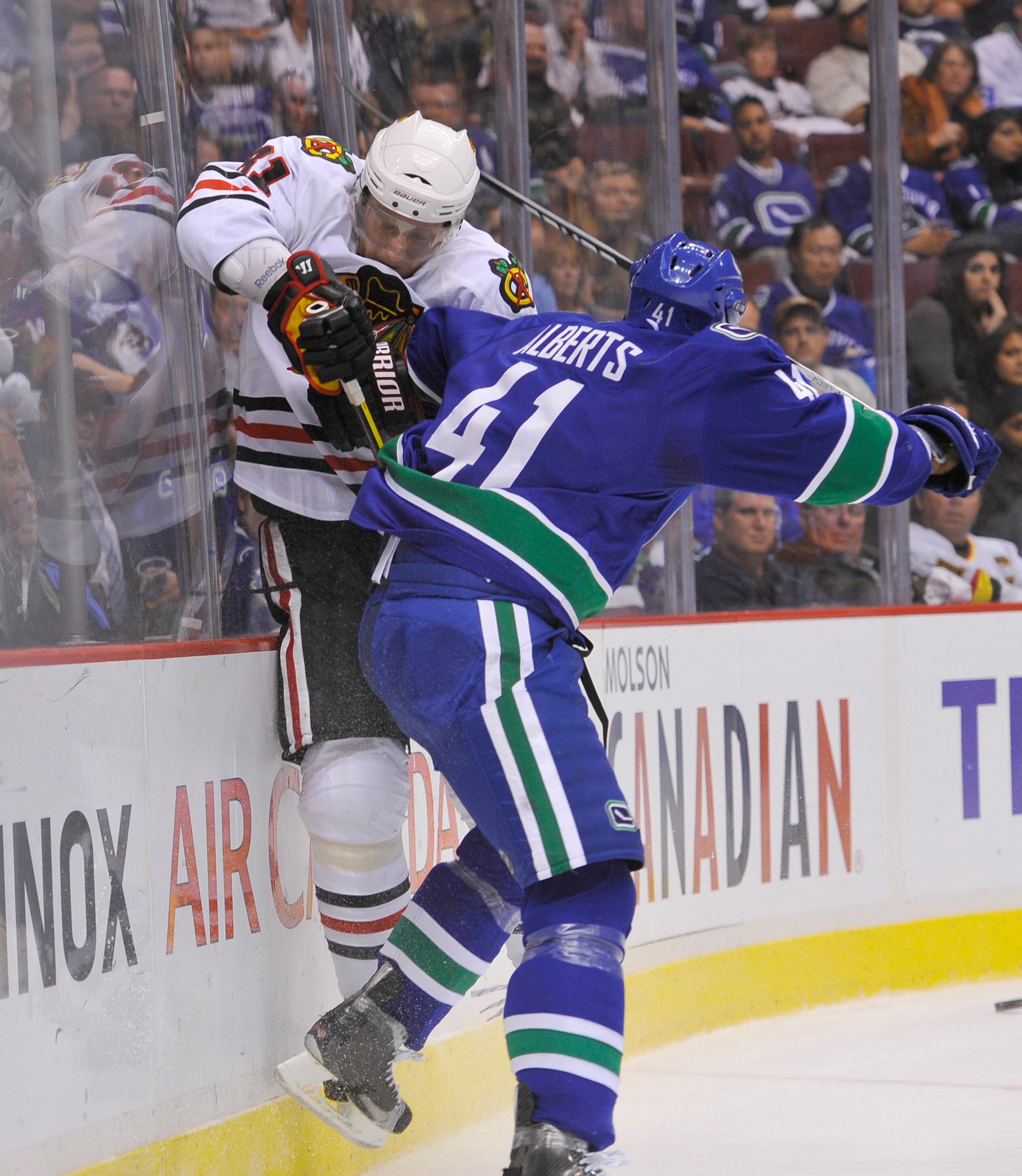 VANCOUVER, CANADA - MAY 11:  Andrew Alberts #4 of the Vancouver Canucks hits Marian Hossa #81 of the Chicago Blackhawks along the end boards during the second period in Game Six of the Western Conference Semifinals during the 2010 NHL Stanley Cup Playoffs