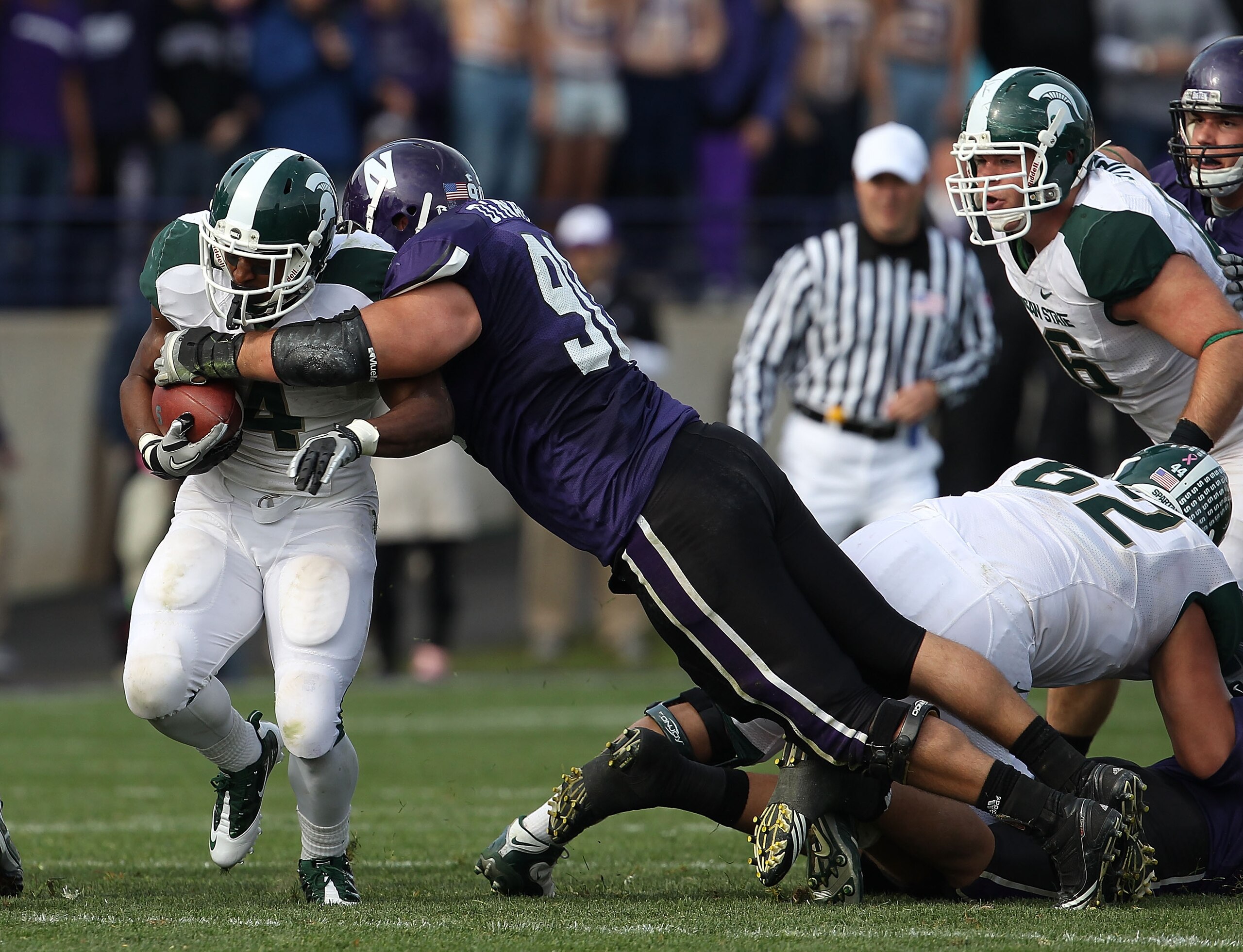 EVANSTON, IL - OCTOBER 23: Edwin Baker #4 of the Michigan State Spartans is tackled by Jack Di Nardo #90 of the Northwestern Wildcats at Ryan Field on October 23, 2010 in Evanston, Illinois. Michigan State defeated Northwestern 35-27. (Photo by Jonathan D