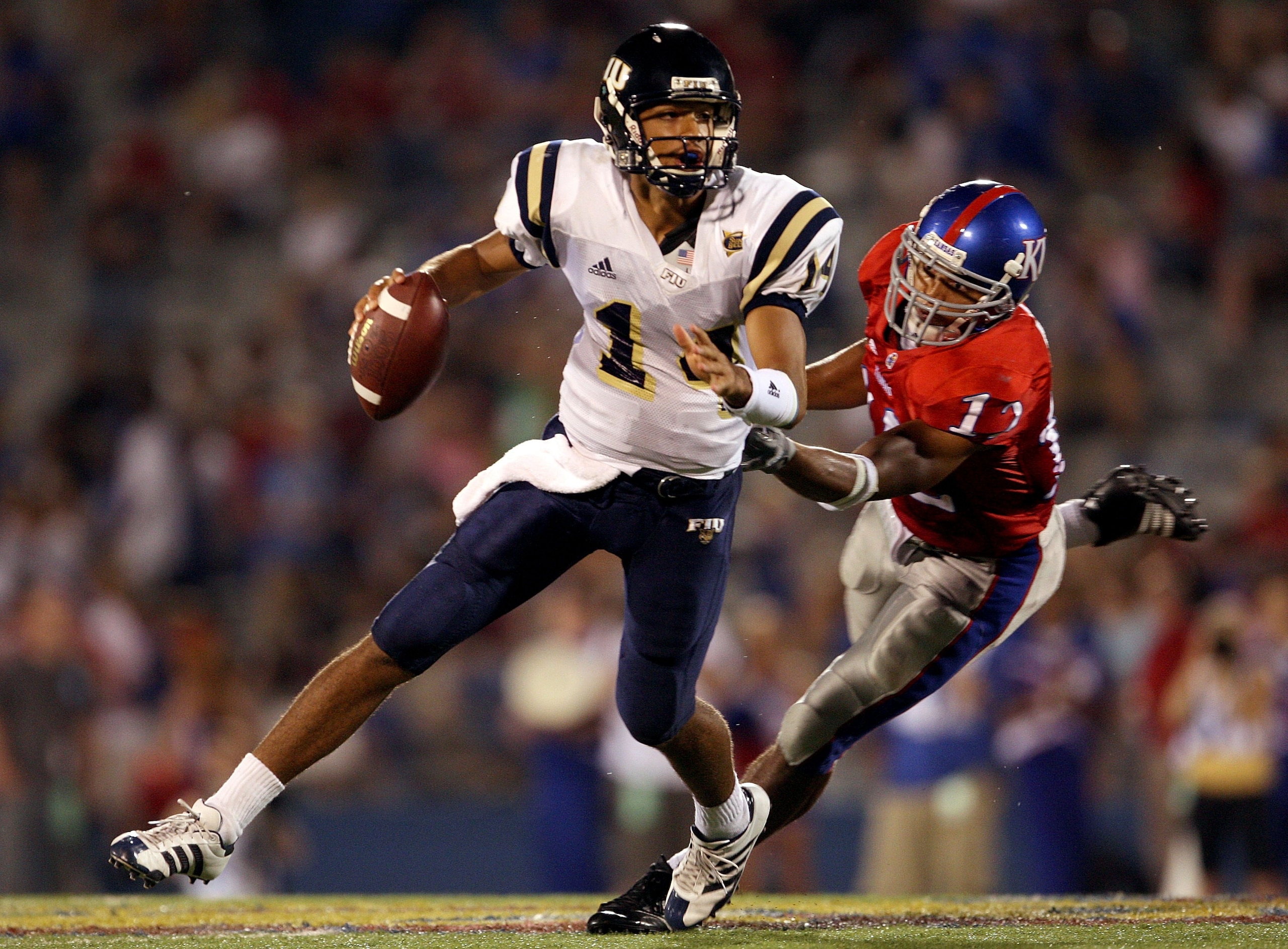 LAWRENCE, KS - SEPTEMBER 22:  Quarterback Wayne Younger #14 of the Florida International Golden Panthers is chased by James Holt #12 of the Kansas Jayhawks during the 2nd half of the game on September 22, 2007 at Memorial Stadium in Lawrence, Kansas.  (Ph