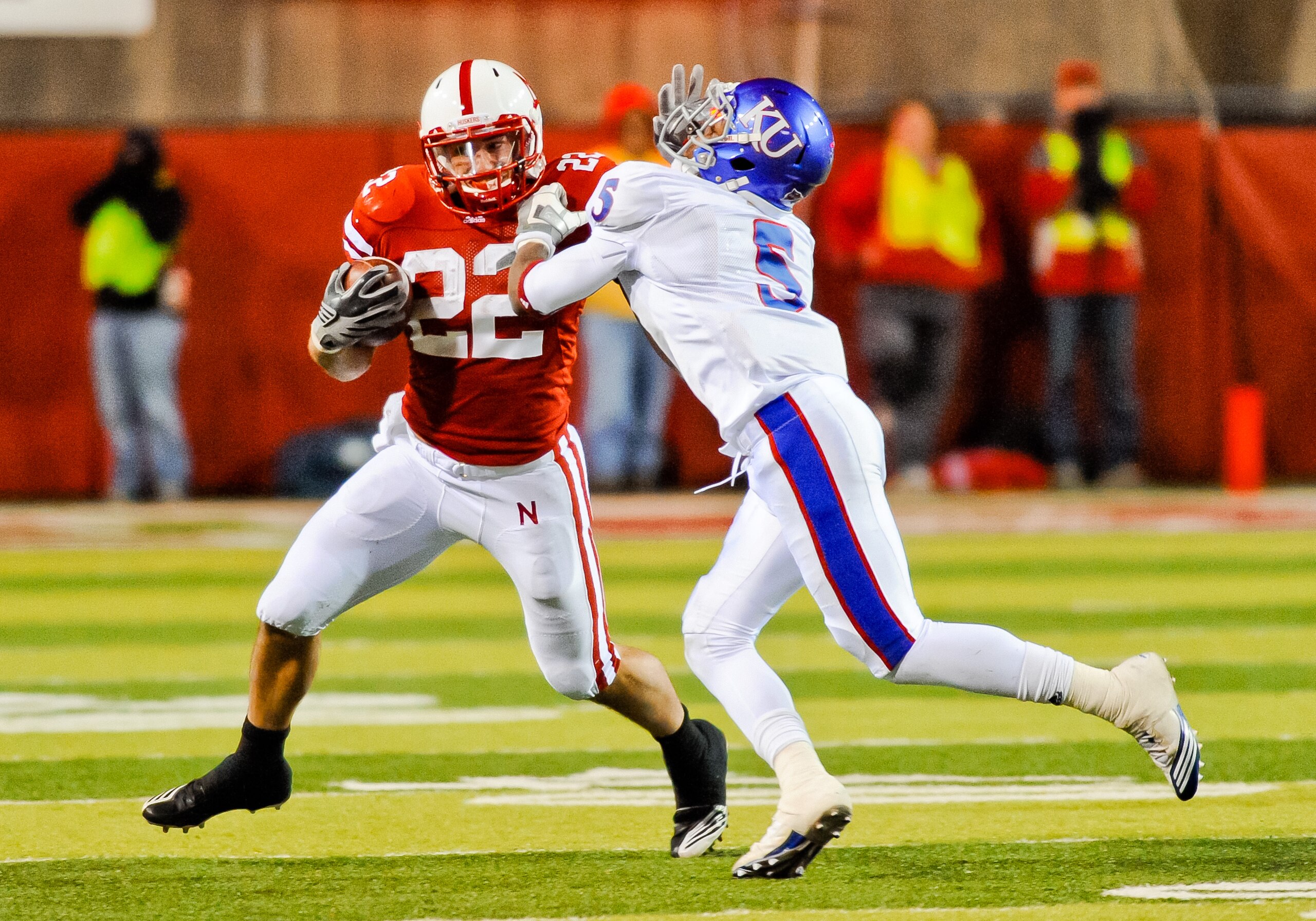 LINCOLN, NE - NOVEMBER 13: Rex Burkhead #22 of the Nebraska Cornhuskers stiff arms Greg Brown #5 of the Kansas Jayhawks during second half action of their game at Memorial Stadium on November 13, 2010 in Lincoln, Nebraska. Nebraska Defeated Kansas 20-3. ( LINCOLN, NE - NOVEMBER 13: Rex Burkhead #22 of the Nebraska Cornhuskers stiff arms Greg Brown #5 of the Kansas Jayhawks during second half action of their game at Memorial Stadium on November 13, 2010 in Lincoln, Nebraska. Nebraska Defeated Kansas 20-3. (