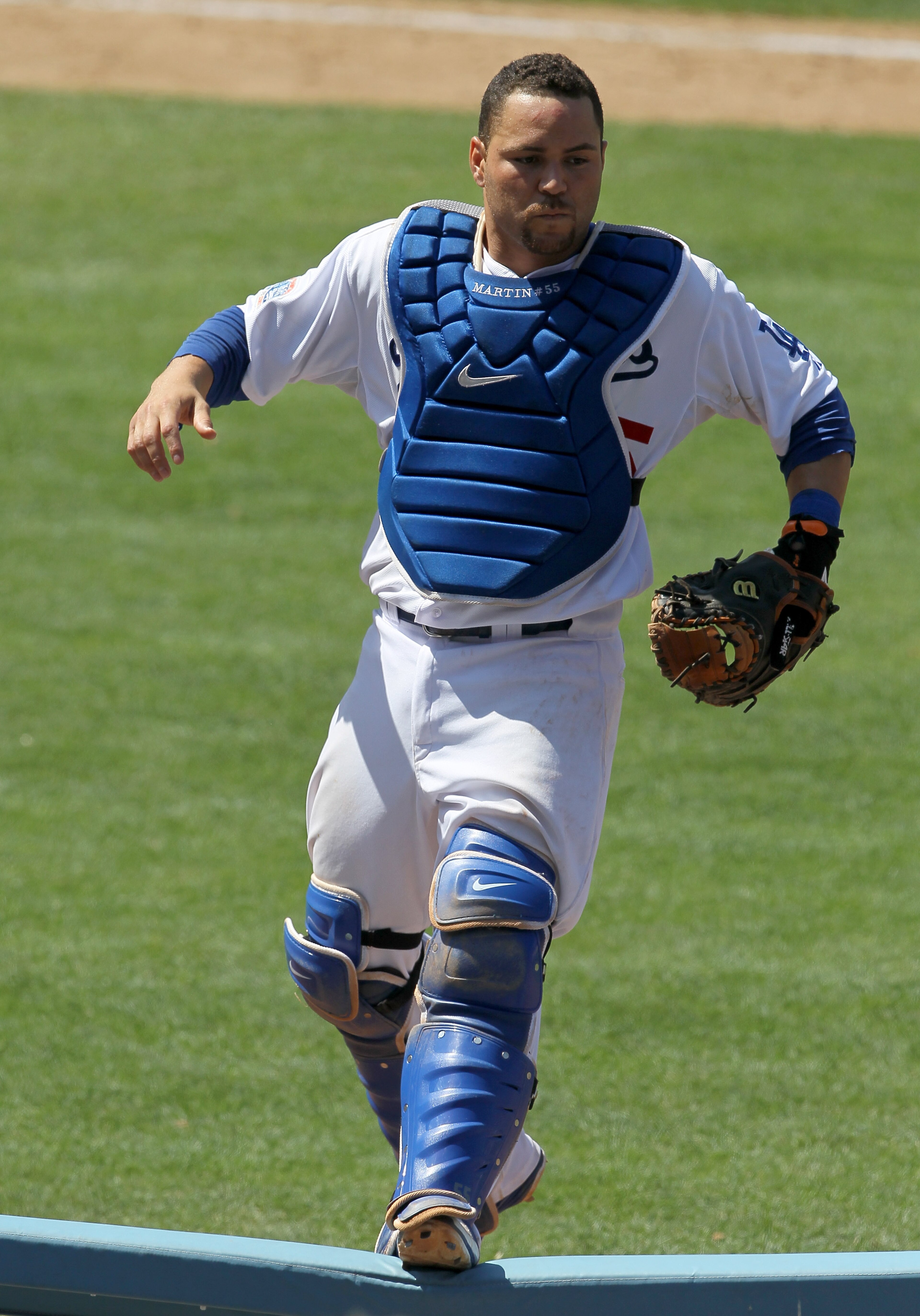 LOS ANGELES, CA - JULY 25: Catcher Russell Martin #55 of the Los Angeles Dodgers jumps onto a rail beside the New York Mets dugouts as he pursues a pop foul ball that fell into the stands on July 25, 2010 at Dodger Stadium in Los Angeles, California. T LOS ANGELES, CA - JULY 25: Catcher Russell Martin #55 of the Los Angeles Dodgers jumps onto a rail beside the New York Mets dugouts as he pursues a pop foul ball that fell into the stands on July 25, 2010 at Dodger Stadium in Los Angeles, California. T