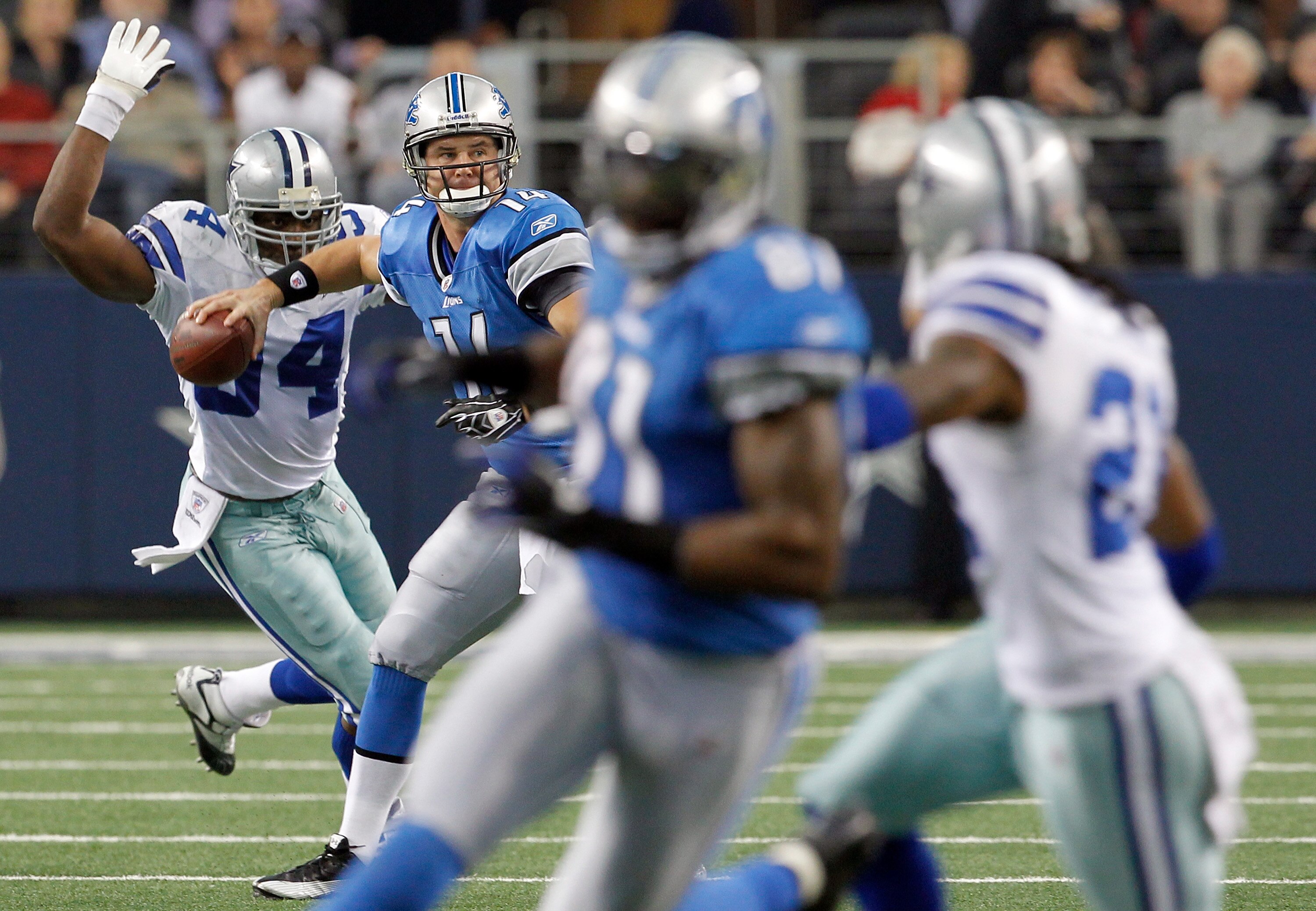 ARLINGTON, TX - NOVEMBER 21:  Shaun Hill #14 of the Detroit Lions looks for an open receiver under pressure by Demarcus Ware #94 of the Dallas Cowboys at Cowboys Stadium on November 21, 2010 in Arlington, Texas.  (Photo by Tom Pennington/Getty Images)