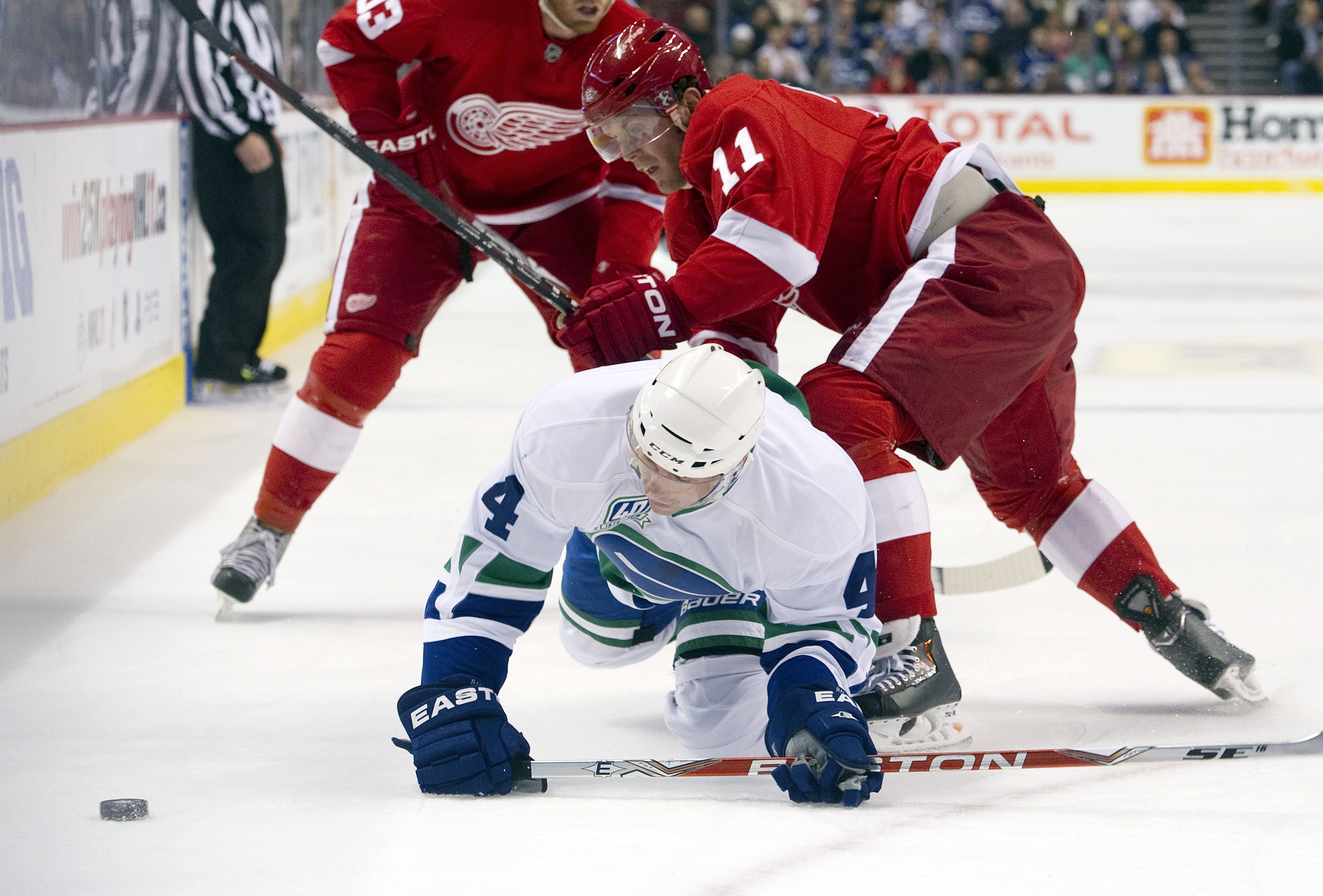 VANCOUVER, CANADA - NOVEMBER 6: Keith Ballard #4 of the Vancouver Canucks gets knocked down to the ice while battling with Dan Cleary #11 of the Detroit Red Wings for the puck during the first period in NHL action on November 06, 2010 at Rogers Arena in V