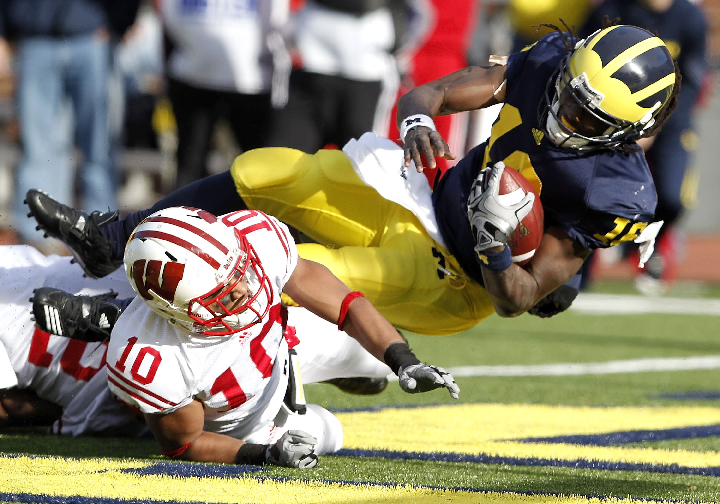 ANN ARBOR, MI - NOVEMBER 20:  Denard Robinson #16 of the Michigan Wolverines dives into the enzone for a fourth quarter touchdown over Devin Smith #10 of the Wisconsin Badgers at Michigan Stadium on November 20, 2010 in Ann Arbor, Michigan. Wisconson won