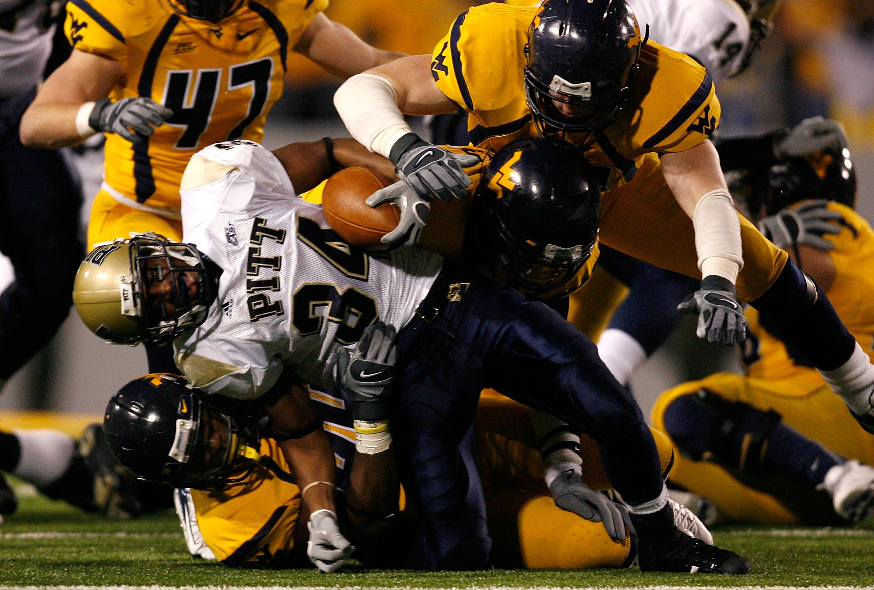 MORGANTOWN, WV - DECEMBER 1:  Running back LaRod Stephens-Howling #34 of the Pittsburgh Panthers is tackled by defenders Mortty Ivy #44, Eric Wicks #41 and Marc Magro #53 of the West Virginia Mountaineers during the first half at Milan Puskar Stadium Dece