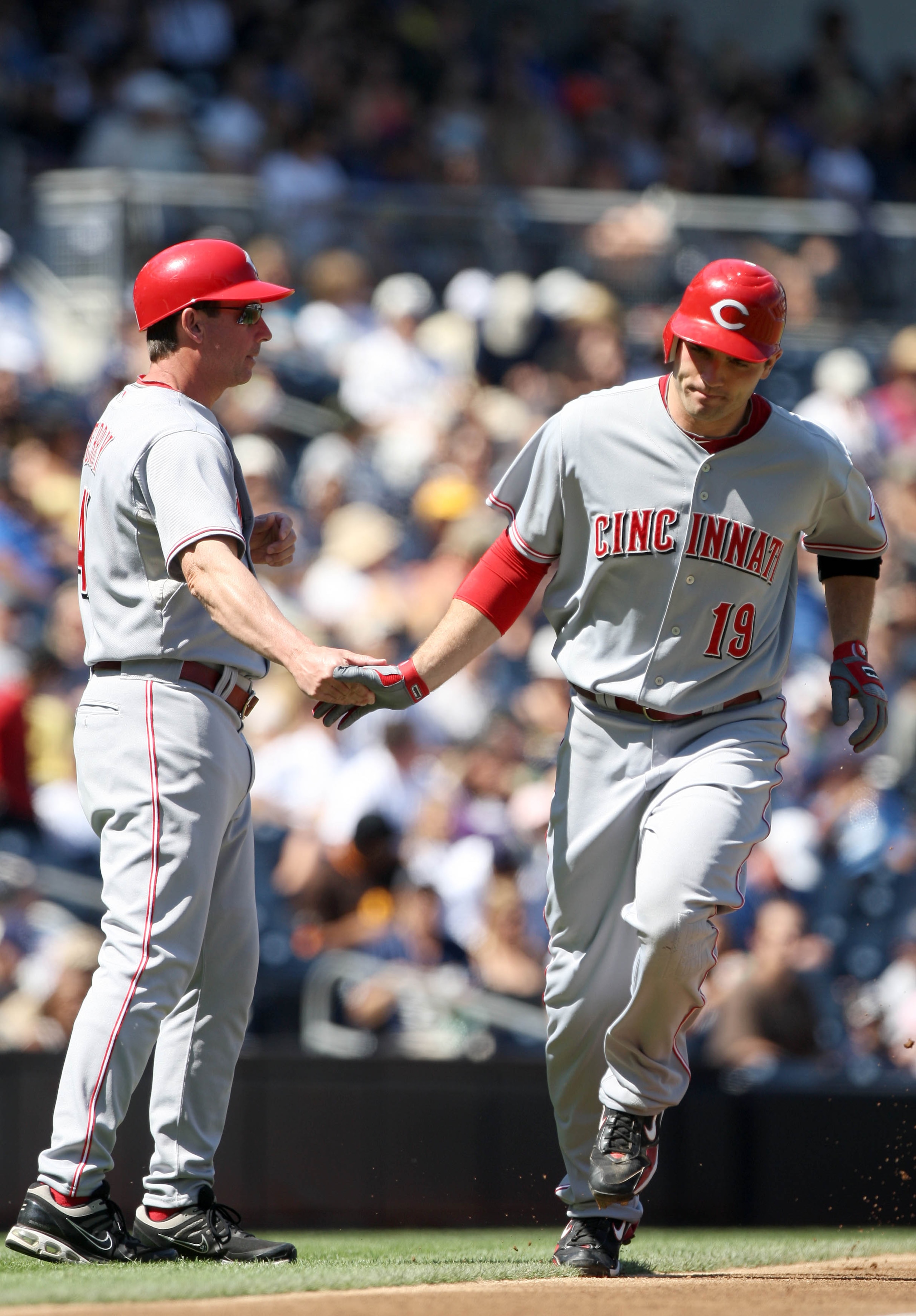 SAN DIEGO, CA - SEPTEMBER 26:  Joey Votto #19 of Cincinnati Reds is greeted by third base coach Mark Berry as he rounds the base after hitting a solo home run against the San Diego Padres during the first inning of their MLB game on September 26, 2010 at
