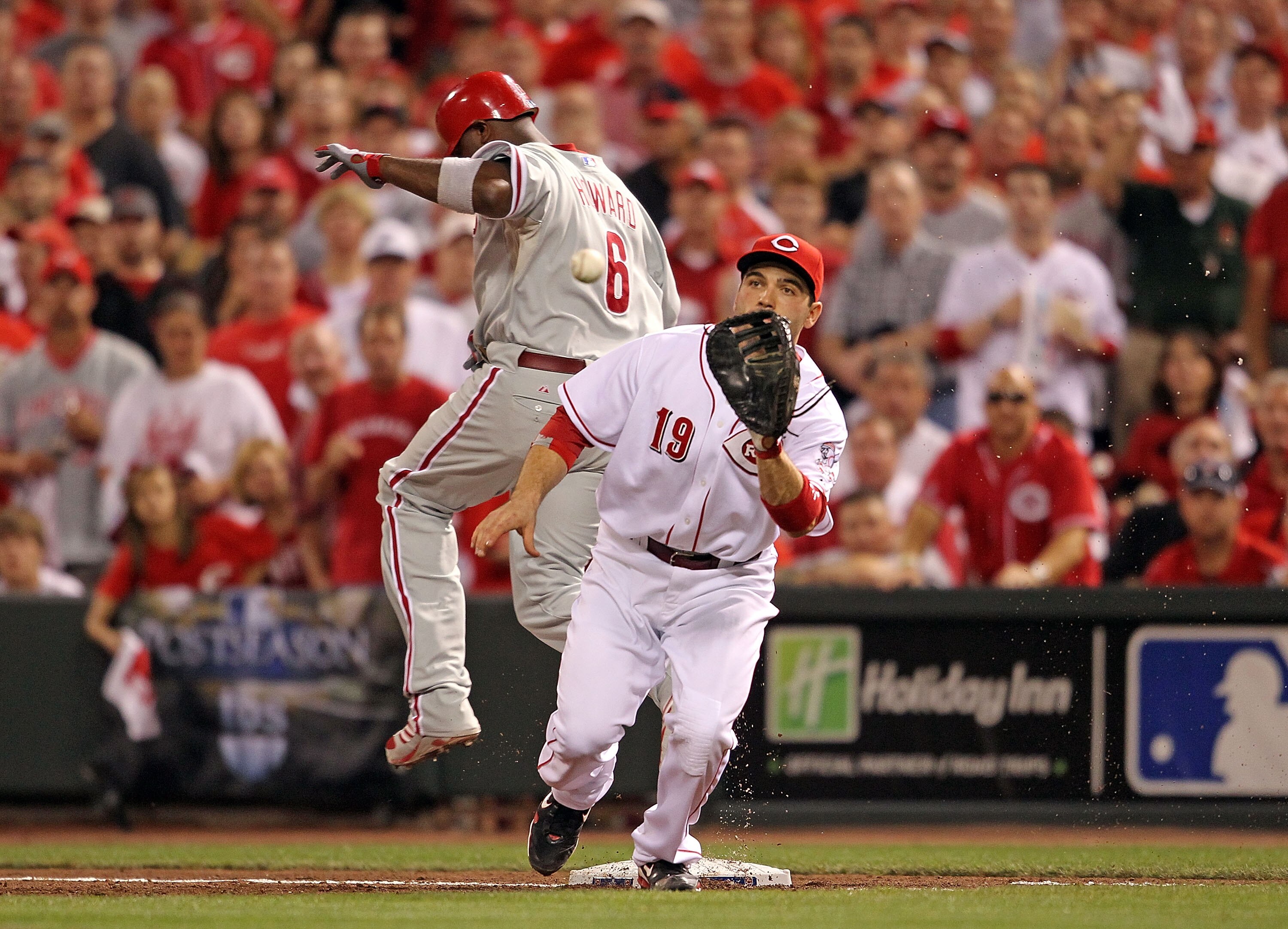 CINCINNATI - OCTOBER 10: Ryan Howard #6 of the Philadelphia Phillies beats the throw and is safe at first base while Joey Votto#19 of the Cincinnati Reds catches the ball  during Game 3 of the NLDS at Great American Ball Park on October 10, 2010 in Cincin