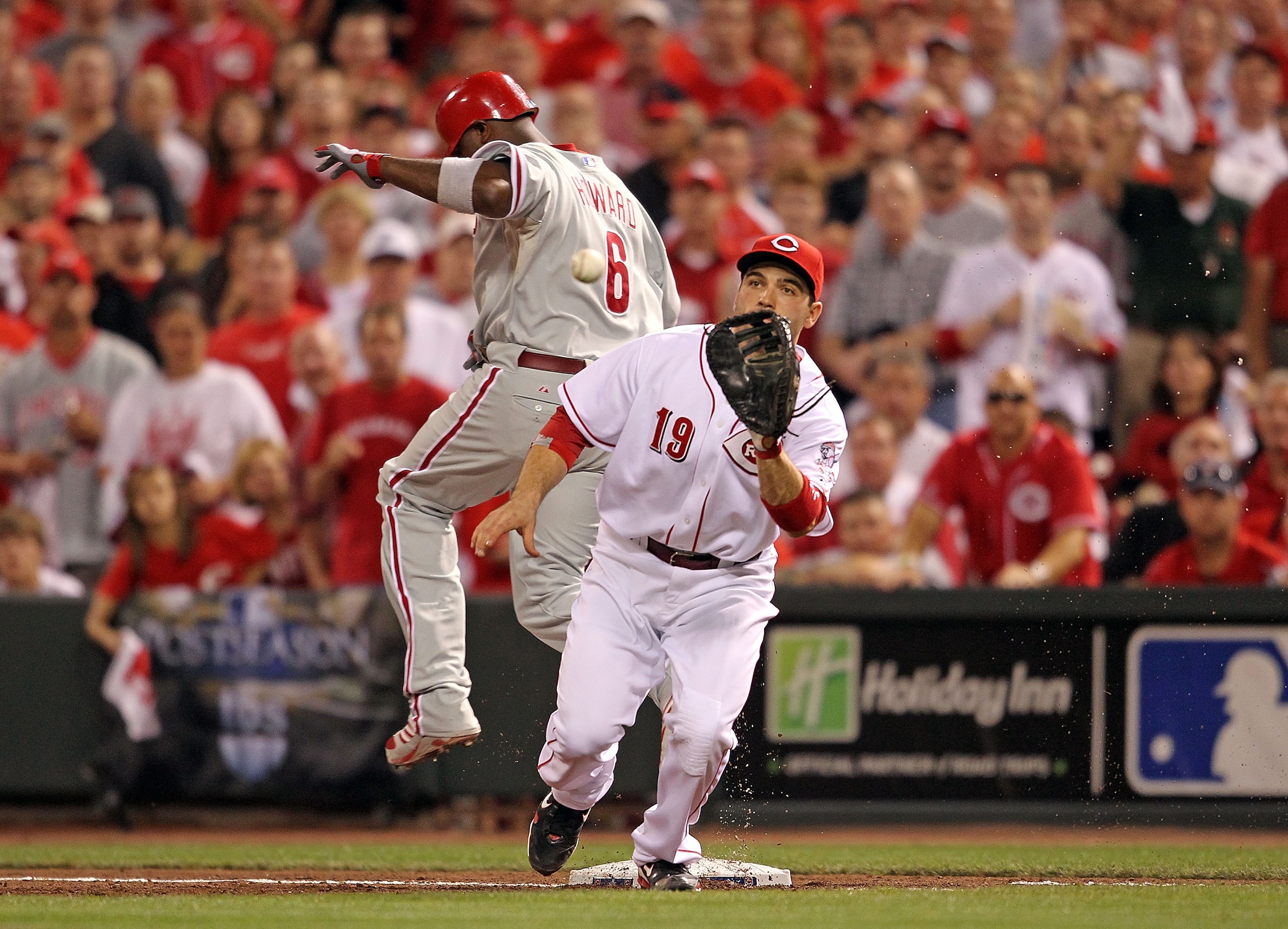 CINCINNATI - OCTOBER 10: Ryan Howard #6 of the Philadelphia Phillies beats the throw and is safe at first base while Joey Votto#19 of the Cincinnati Reds catches the ball  during Game 3 of the NLDS at Great American Ball Park on October 10, 2010 in Cincin
