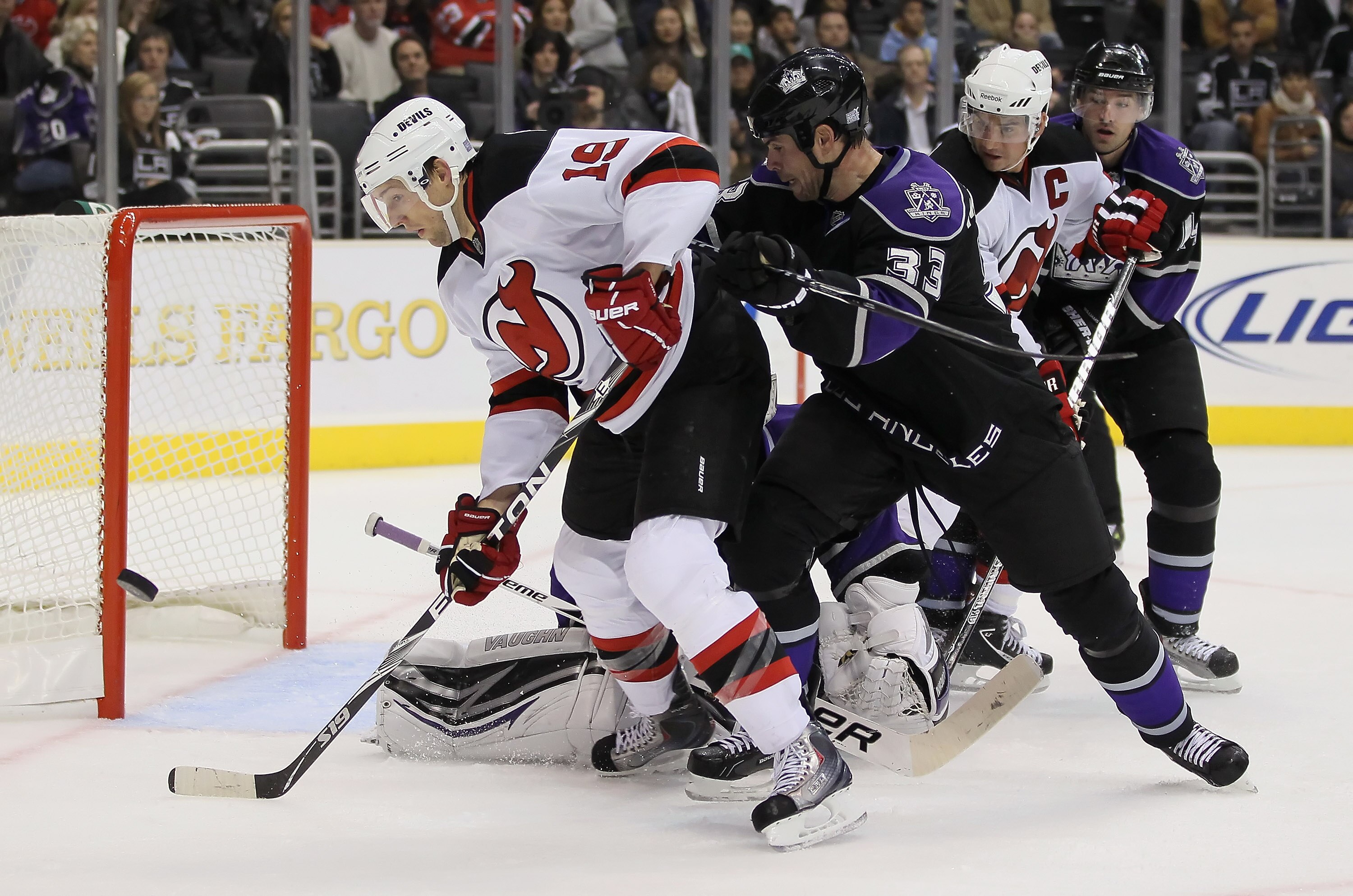 LOS ANGELES, CA - OCTOBER 30:  Travis Zajac #19 of the New Jersey Devils tips the puck wide of the net while being checked by Willie Mitchell #33 of the Los Angeles Kings in the third period at Staples Center on October 30, 2010 in Los Angeles, California