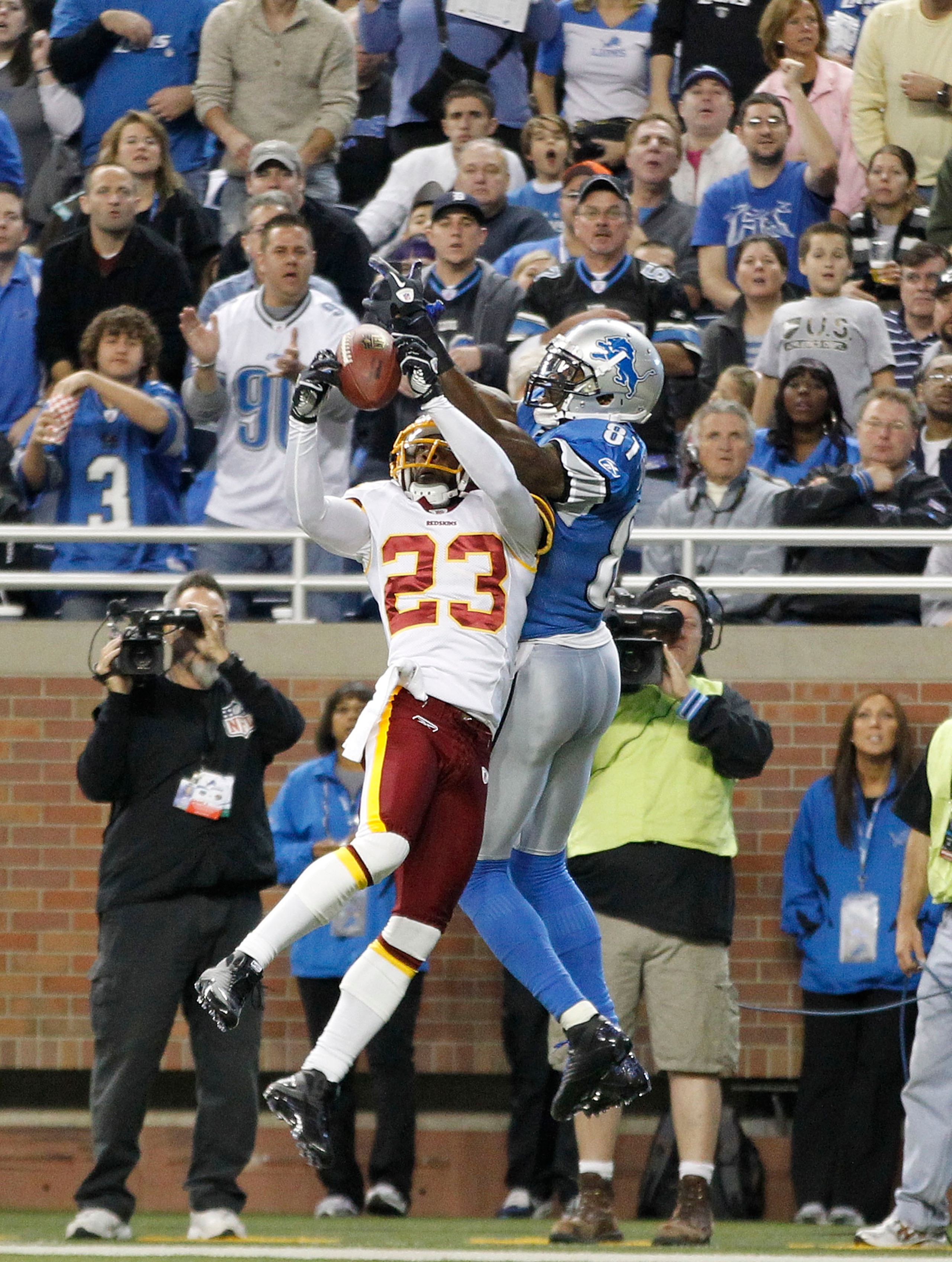 DETROIT - OCTOBER 31:  DeAngelo Hall #23 of the Washingon Redskins intercepts the pass during the second quarter as Calvin Johnson #81 of the Detroit Lions atempts to defend during the game at Ford Field on October 31, 2010 in Detroit, Michigan.  (Photo b