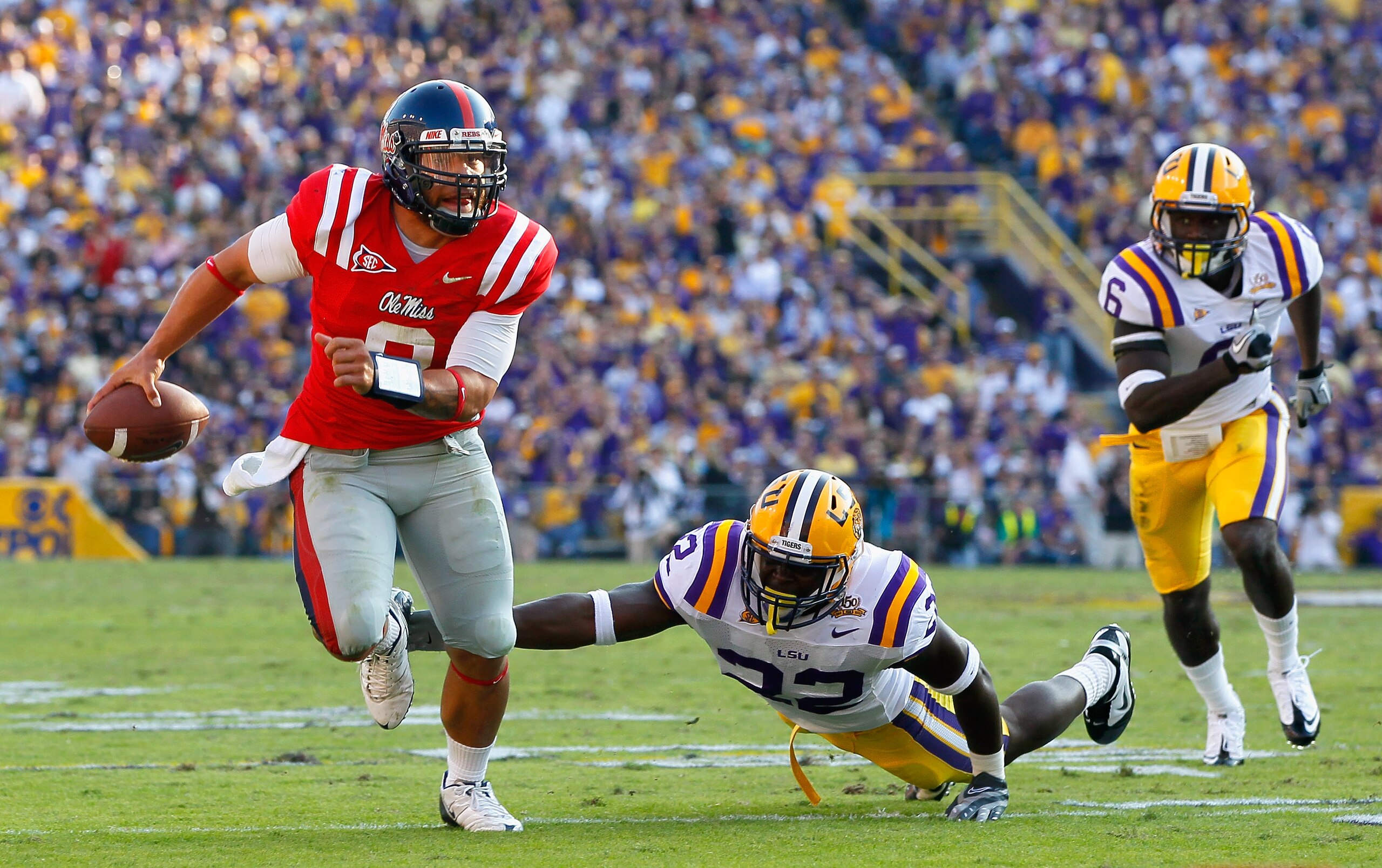 BATON ROUGE, LA - NOVEMBER 20:  Quarterback Jeremiah Masoli #8 of the Ole Miss Rebels breaks away from Ryan Baker #22 and Craig Loston #6 of the Louisiana State University Tigers at Tiger Stadium on November 20, 2010 in Baton Rouge, Louisiana.  (Photo by
