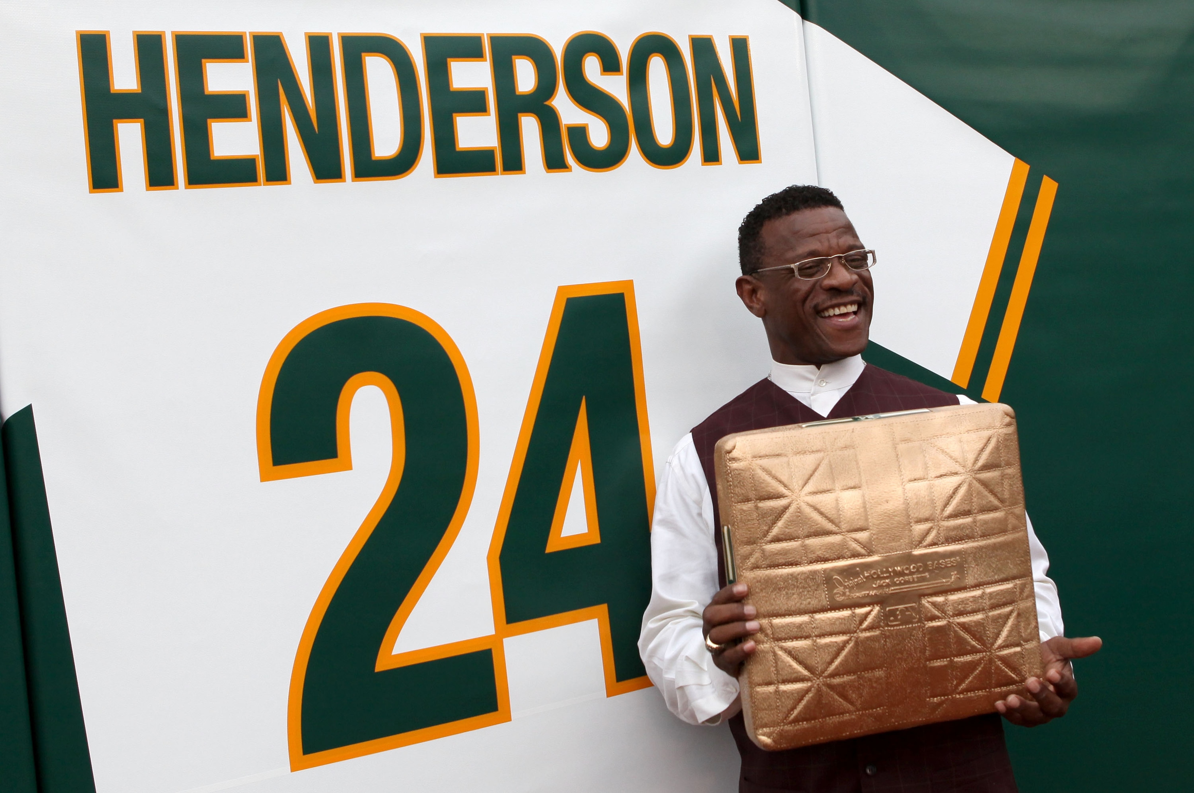 OAKLAND, CA - AUGUST 01:  Hall of Fame baseball player Rickey Henderson stands in front of his retired jersey during a ceremony to retire his number 24 by the Oakland Athletics before the start of the game against the Toronto Blue Jays August 1, 2009 at t