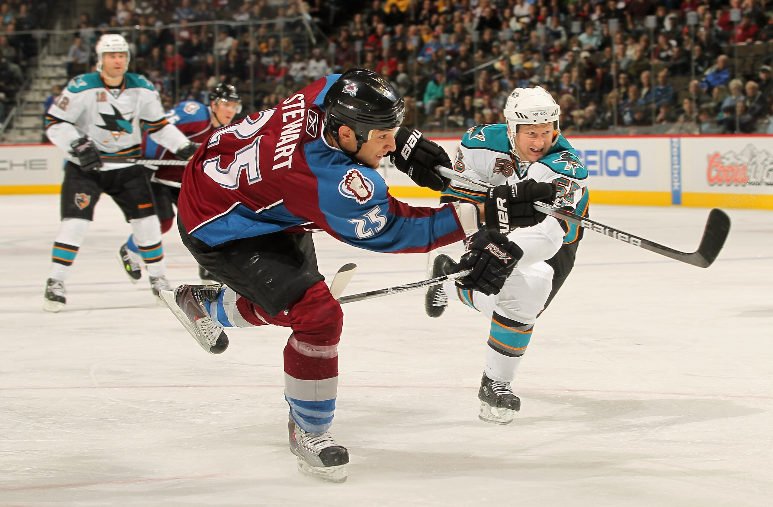 DENVER - NOVEMBER 17:  Chris Stewart #25 (C) of the Colorado Avalanche follows through on his third period goal as Mike Moore #55 of the San Jose Sharks defends at the Pepsi Center on November 17, 2010 in Denver, Colorado. The Avalanche defeated the Shark