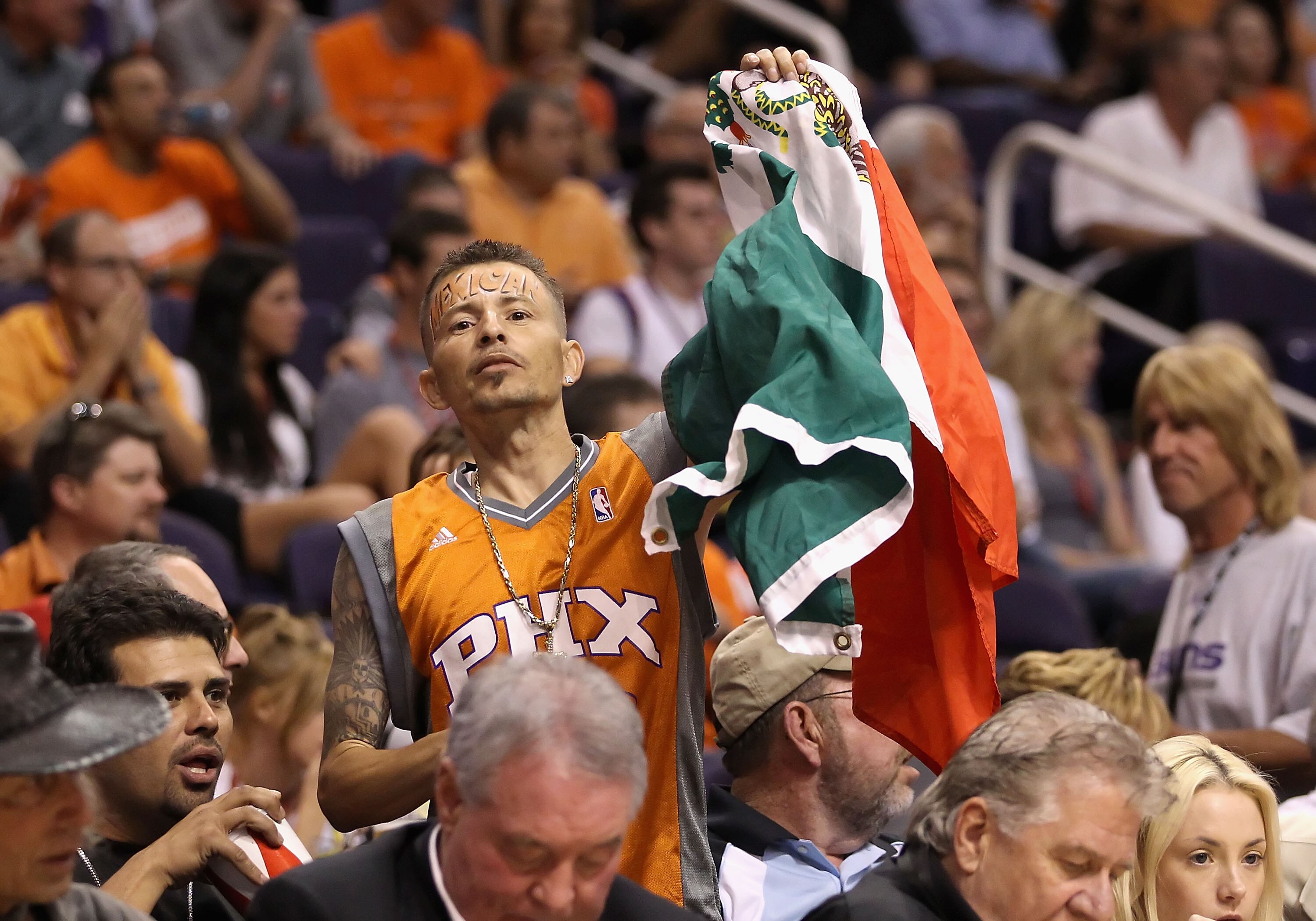 PHOENIX - MAY 05:  A Phoenix Suns fan holds up a Mexican flag as he cheers during Game Two of the Western Conference Semifinals of the 2010 NBA Playoffs against the San Antonio Spurs at US Airways Center on May 5, 2010 in Phoenix, Arizona. The team is wea
