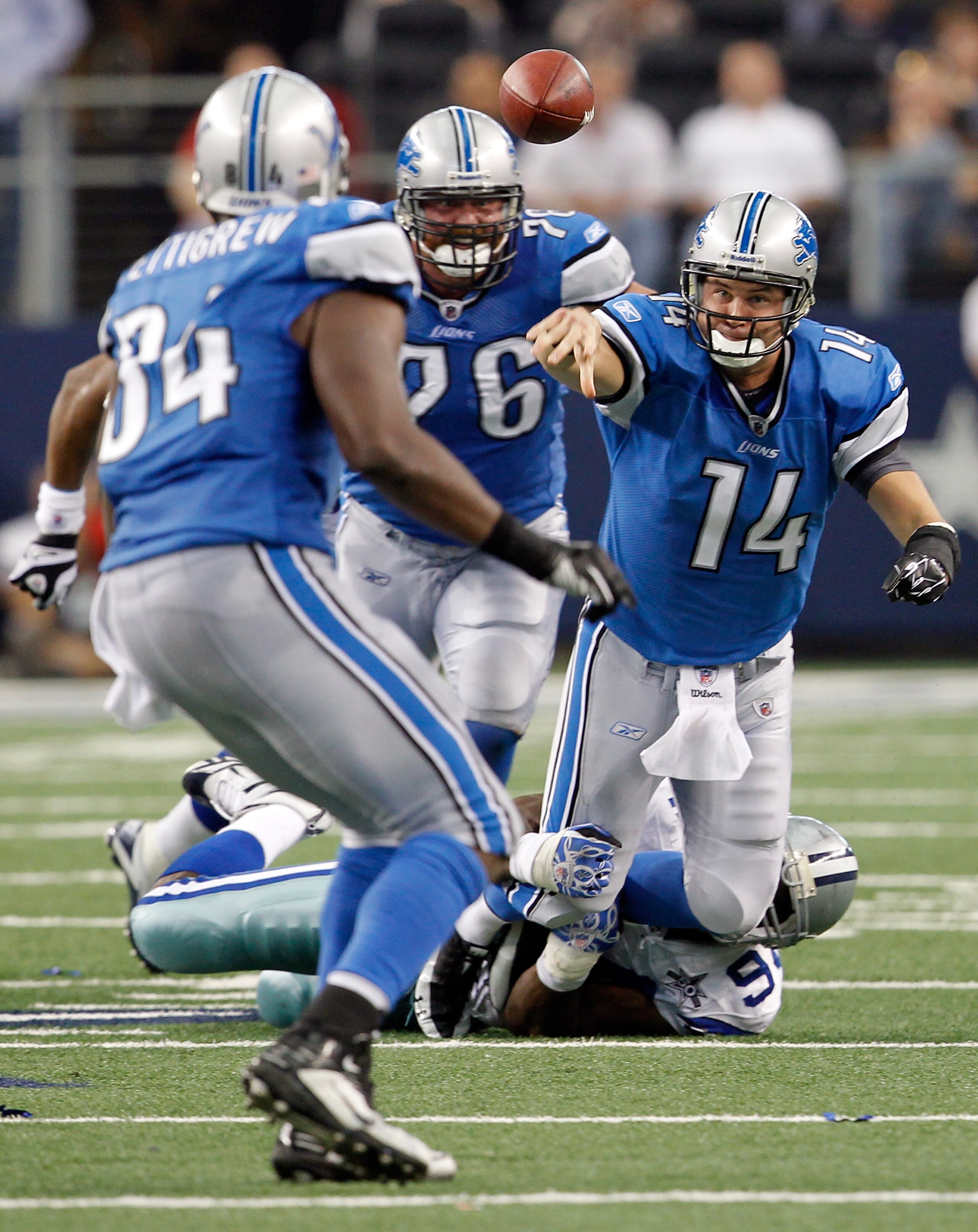 ARLINGTON, TX - NOVEMBER 21:  Shaun Hill #14 of the Detroit Lions throws a pass while being tackled by Demarcus Ware #94 of the Dallas Cowboys at Cowboys Stadium on November 21, 2010 in Arlington, Texas.  (Photo by Tom Pennington/Getty Images)