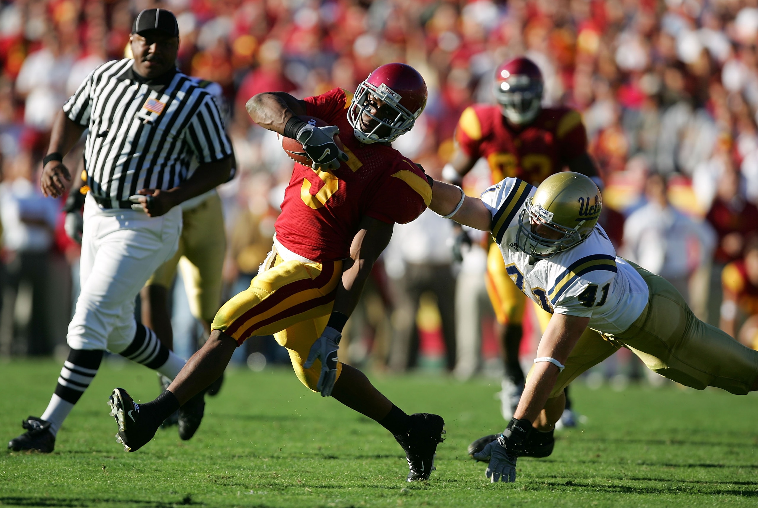 LOS ANGELES, CA - DECEMBER 03:  Reggie Bush #5 of the USC Trojans tries to break free of the grasp of Spencer Havner #41 of the UCLA Bruins December 3, 2005 at the Los Angeles Memorial Coliseum in Los Angeles, California.  (Photo by Harry How/Getty Images