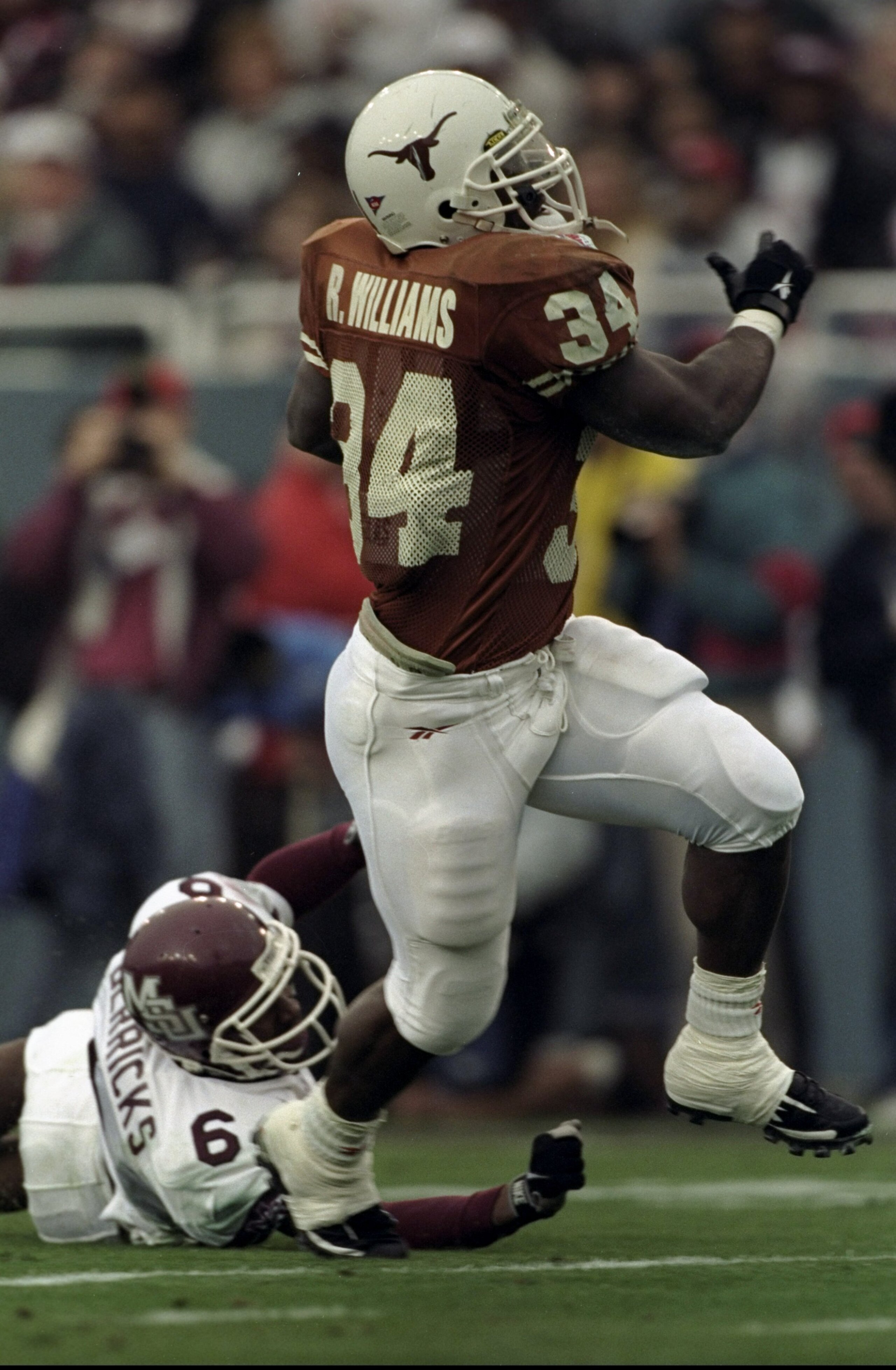 3 Jan 1999: Ricky Williams #34 of the Texas Longhorns breaks through a tackle by Anthony Derricks #6 during the Southwestern Bell Cotton Bowl against the Mississippi State Bulldogs at the Cotton Bowl in Dallas, Texas. Texas defeated Mississippi St. 38-11.