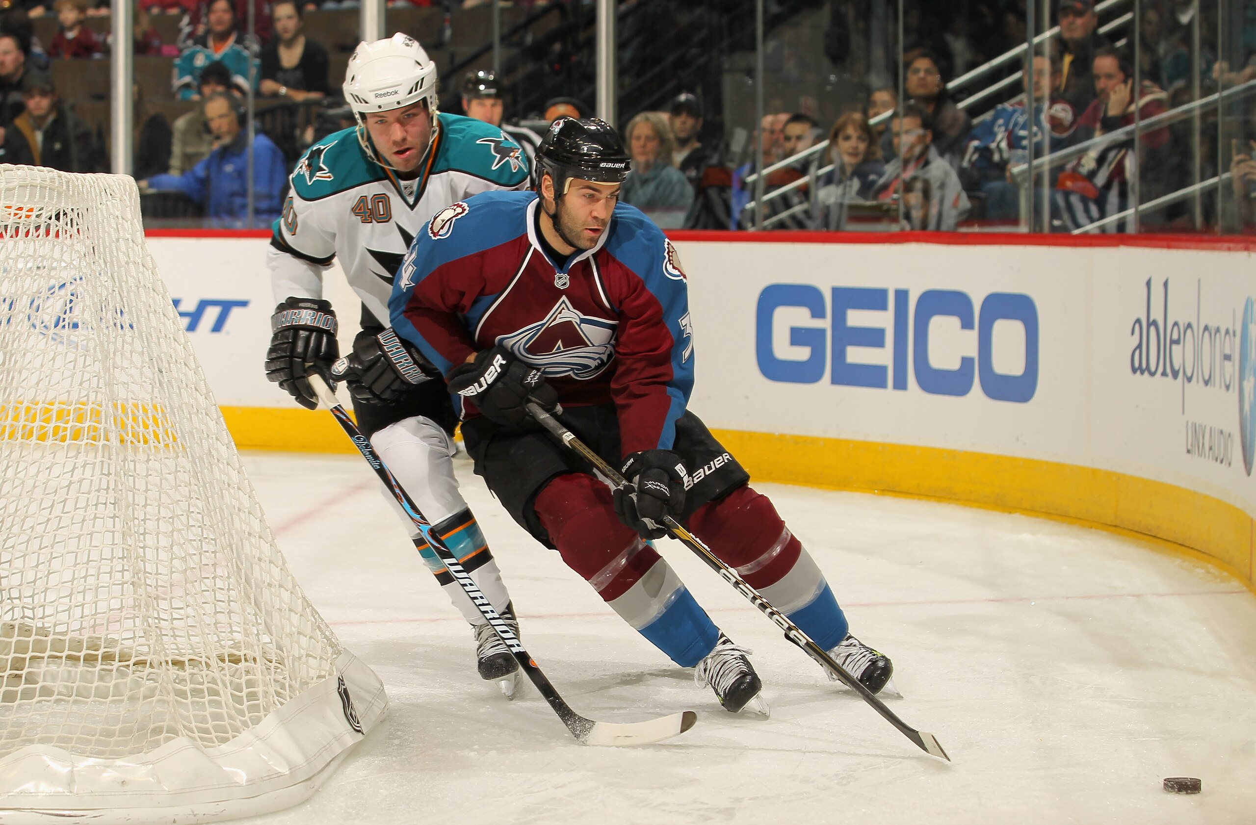 DENVER - NOVEMBER 17:  Daniel Winnik #34 of the Colorado Avalanche tries to collect the puck while under pressure from Kent Huskins #40 of the San Jose Sharks at the Pepsi Center on November 17, 2010 in Denver, Colorado.  (Photo by Doug Pensinger/Getty Im