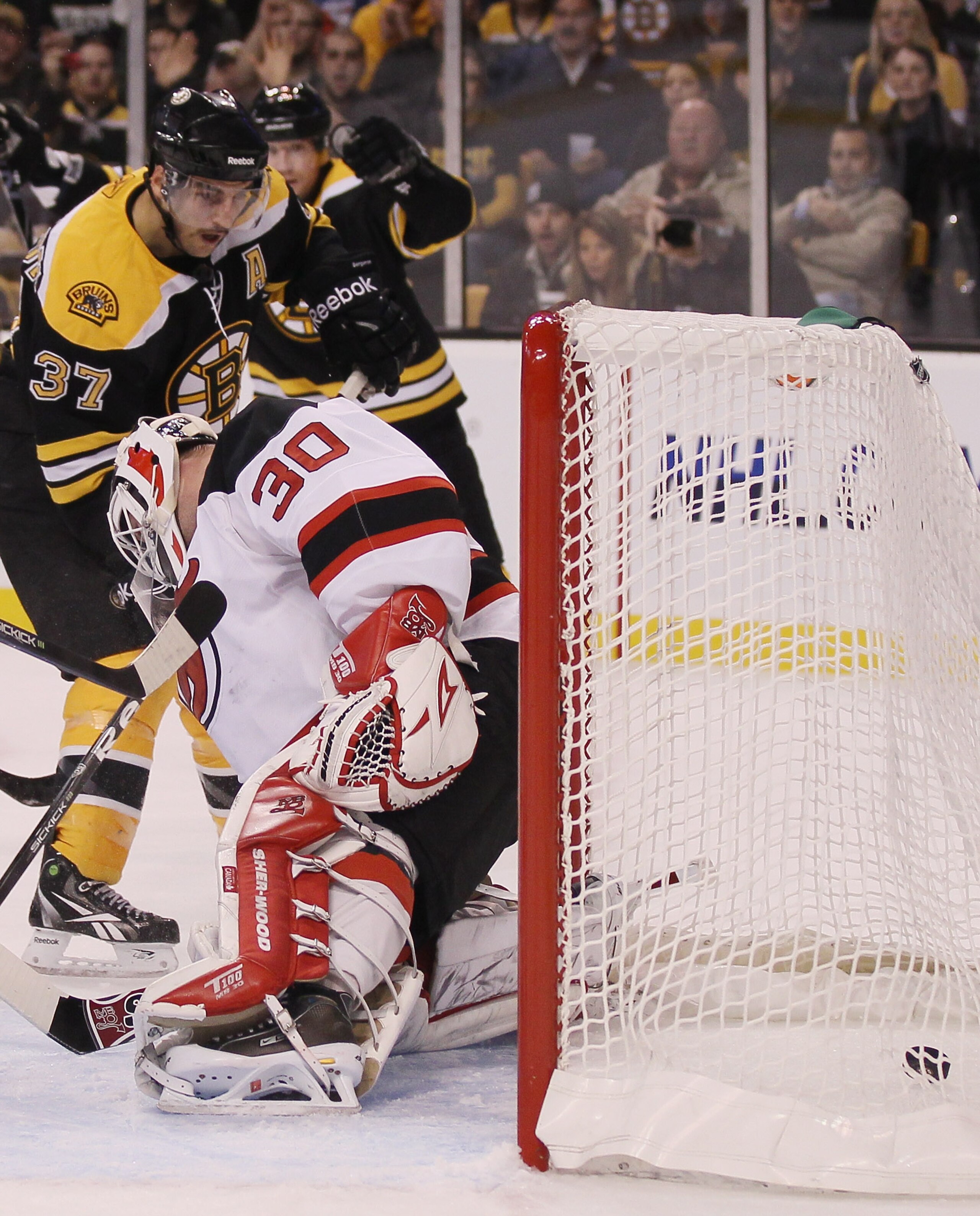 BOSTON - NOVEMBER 15:  Patrice Bergeron #37 of the Boston Bruins gets the assist as the puck slips past Martin Brodeur #30 of the New Jersey Devils on November 15, 2010 at the TD Garden in Boston, Massachusetts.  (Photo by Elsa/Getty Images)