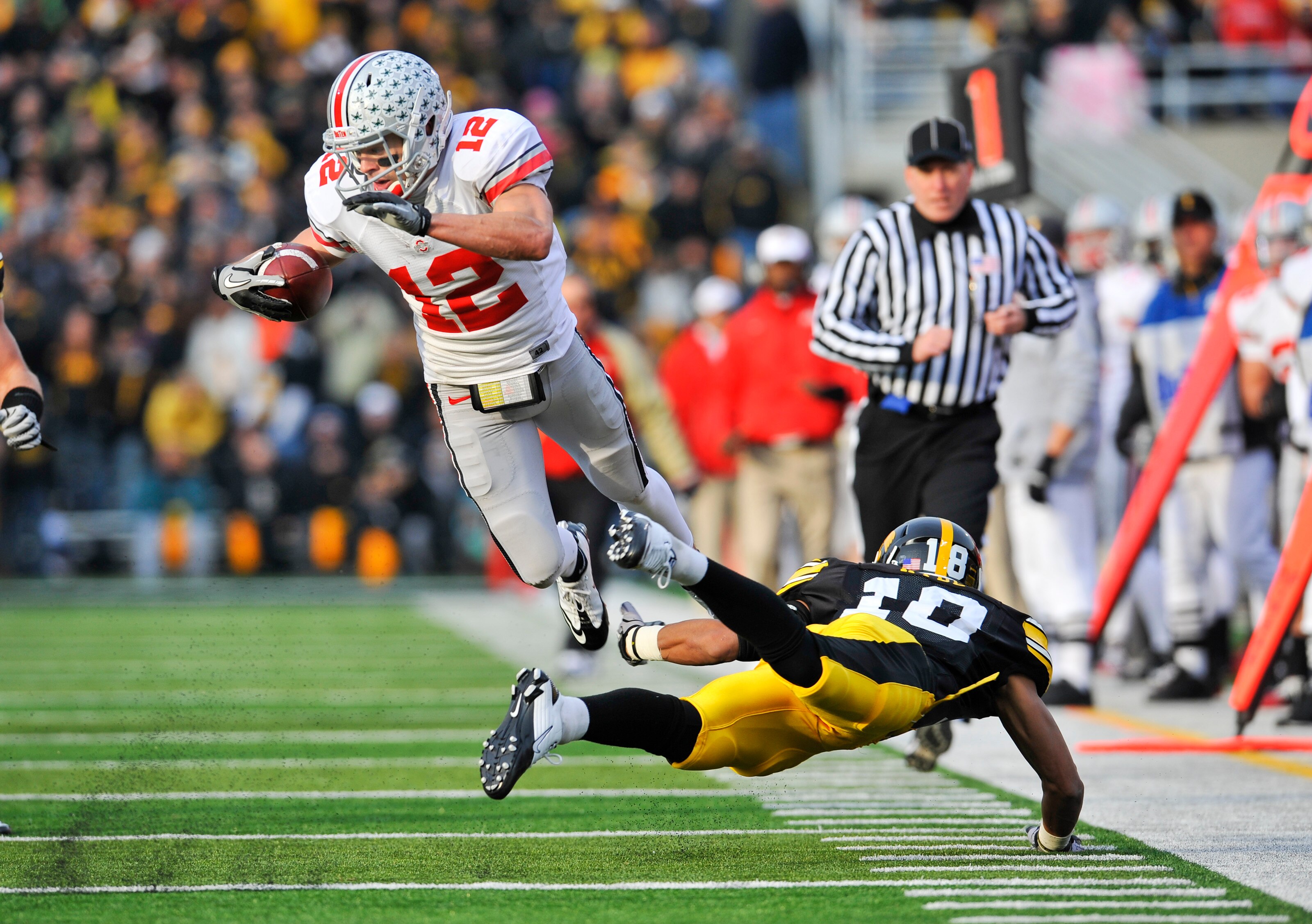 IOWA CITY, IA - NOVEMBER 20: Defenisve back Micah Hyde #18 of the University of Iowa Hawkeyes trips up wide receiver Dane Sanzenbacher #12 of the Ohio State Buckeyes as he drove the ball down field during the first half of play at Kinnick Stadium on Novem
