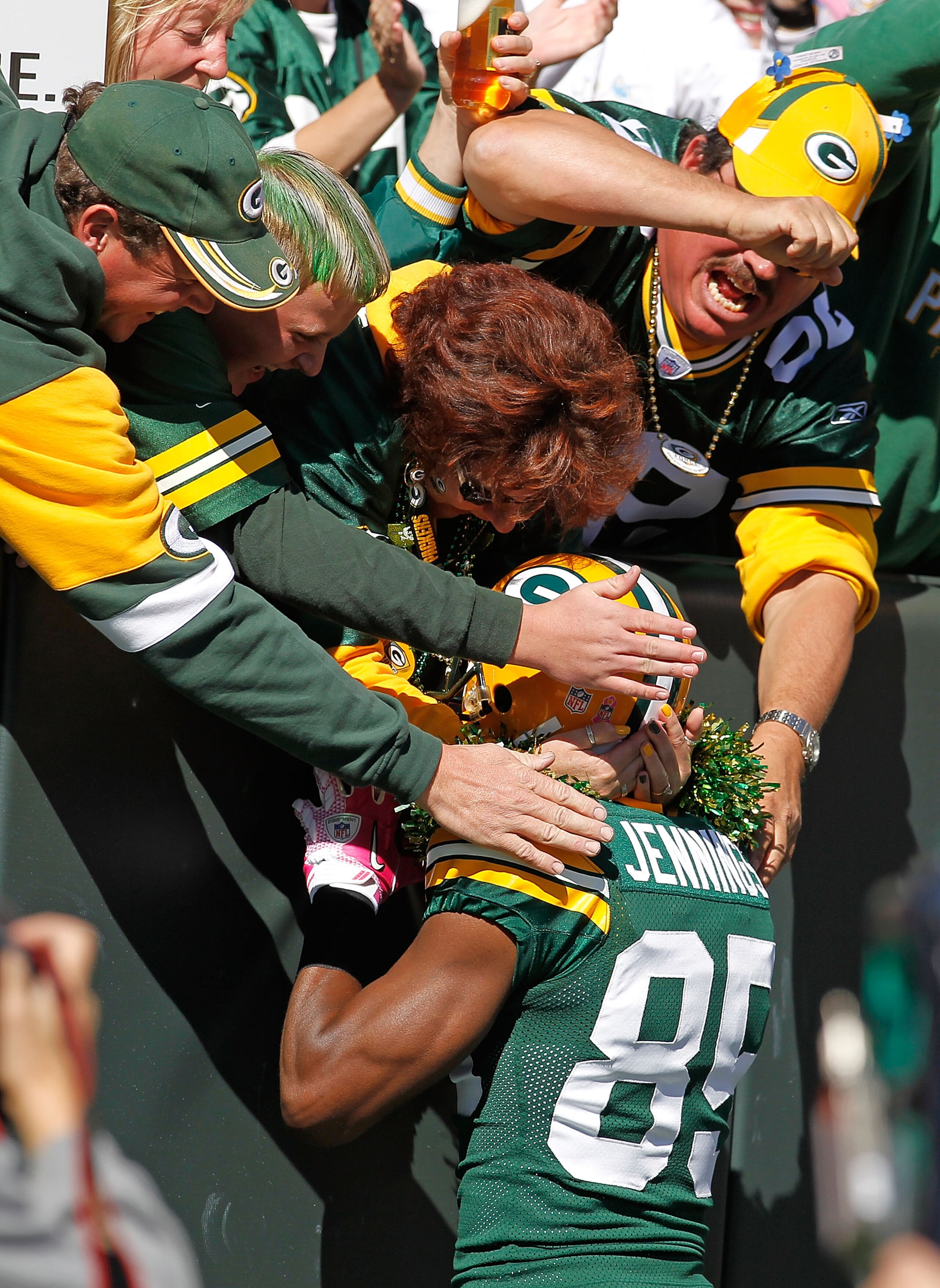 GREEN BAY, WI - OCTOBER 03: Greg Jennings #85 of the Green Bay Packers is grabbed by fans after scoring a first half touchdown against the Detroit Lions at Lambeau Field on October 3, 2010 in Green Bay, Wisconsin. The Packers defeated the Lions 28-26. (Ph