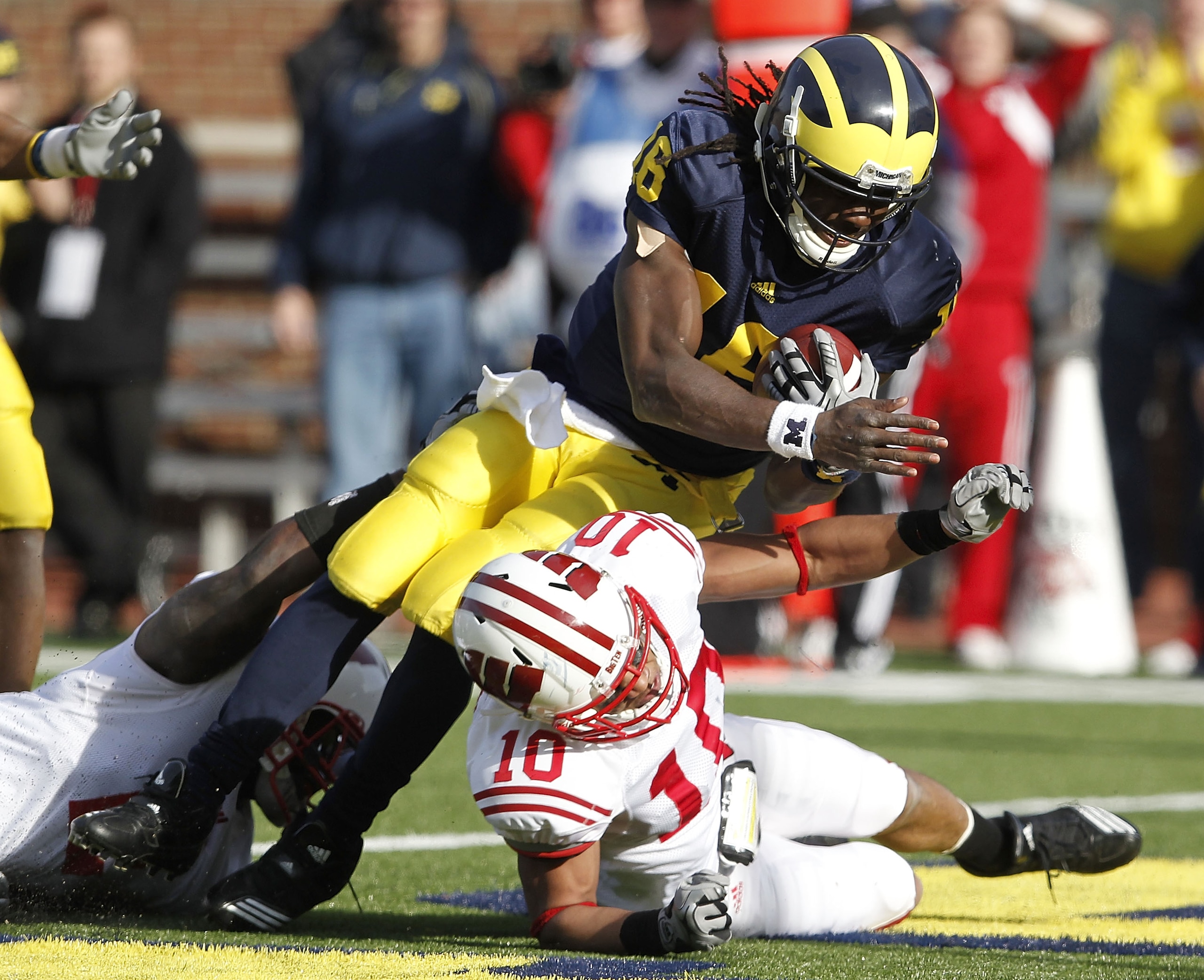 ANN ARBOR, MI - NOVEMBER 20:  Denard Robinson #16 of the Michigan Wolverines dives into the enzone for a fourth quarter touchdown over Devin Smith #10 of the Wisconsin Badgers at Michigan Stadium on November 20, 2010 in Ann Arbor, Michigan. Wisconson won