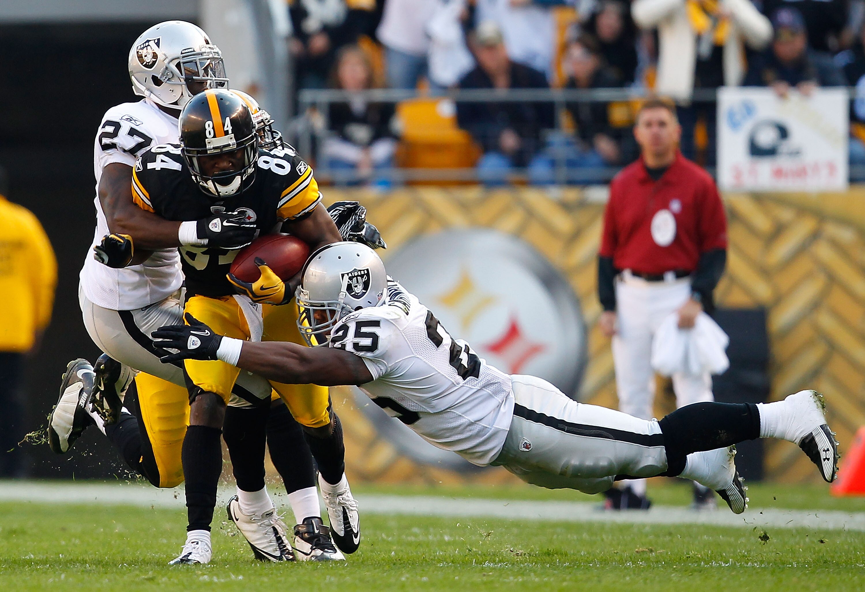 PITTSBURGH - NOVEMBER 21:  Antonio Brown #84 of the Pittsburgh Steelers attempts to run through tackles by Stevie Brown #27 and Rock Cartwright #25 of the Oakland Raiders during the game on November 21, 2010 at Heinz Field in Pittsburgh, Pennsylvania.  (P