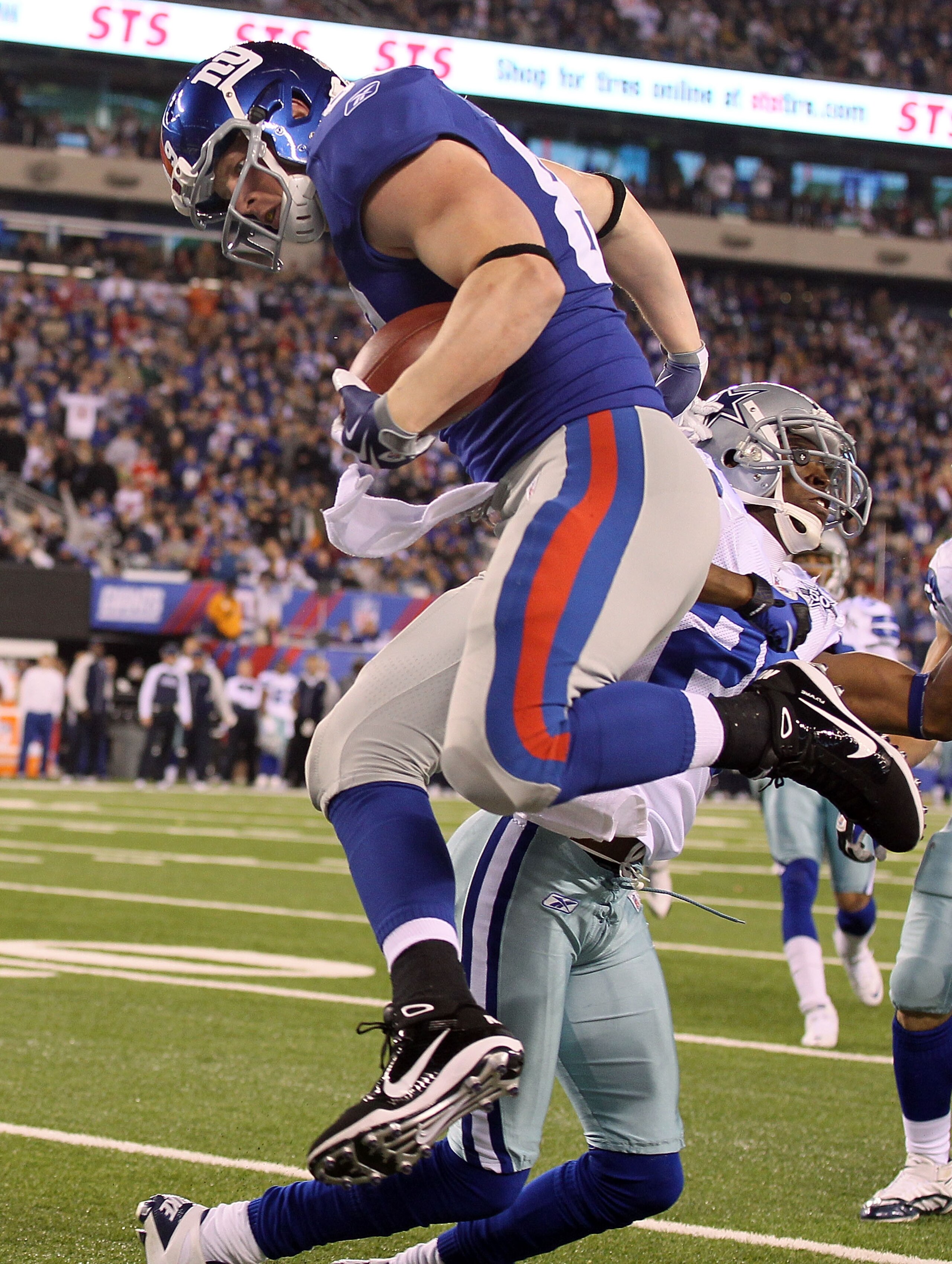 EAST RUTHERFORD, NJ - NOVEMBER 14:  Kevin Boss #89 of the New York Giants jumps past Alan Ball #20 of the Dallas Cowboys and into the endzone for a third quarter touchdown on November 14, 2010 at the New Meadowlands Stadium in East Rutherford, New Jersey.