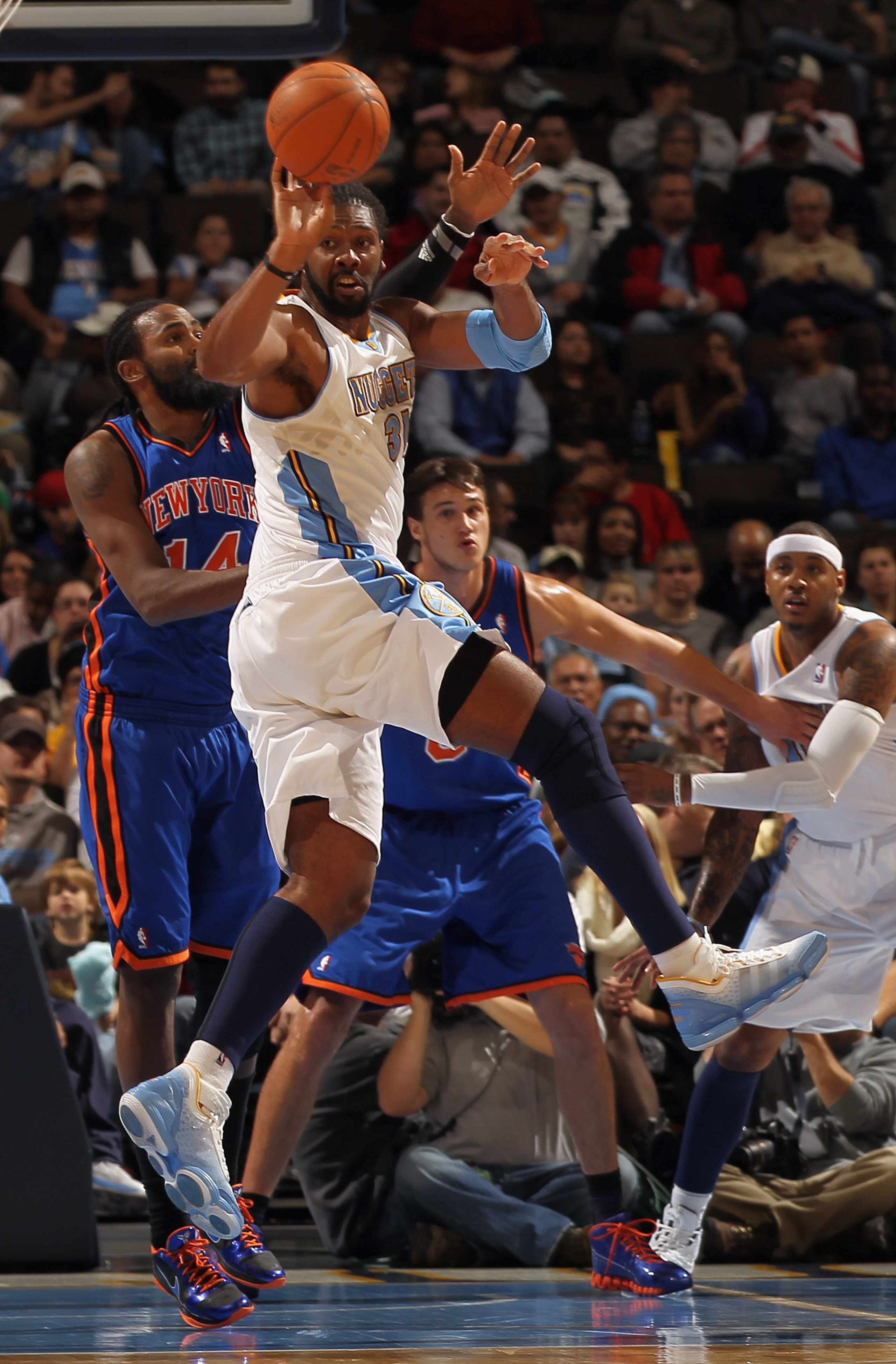 DENVER - NOVEMBER 16:  Nene #31 of the Denver Nuggets passes the ball while under defensive pressure from Ronny Turiaf #14 of the New York Knicks at the Pepsi Center on November 16, 2010 in Denver, Colorado. NOTE TO USER: User expressly acknowledges and a