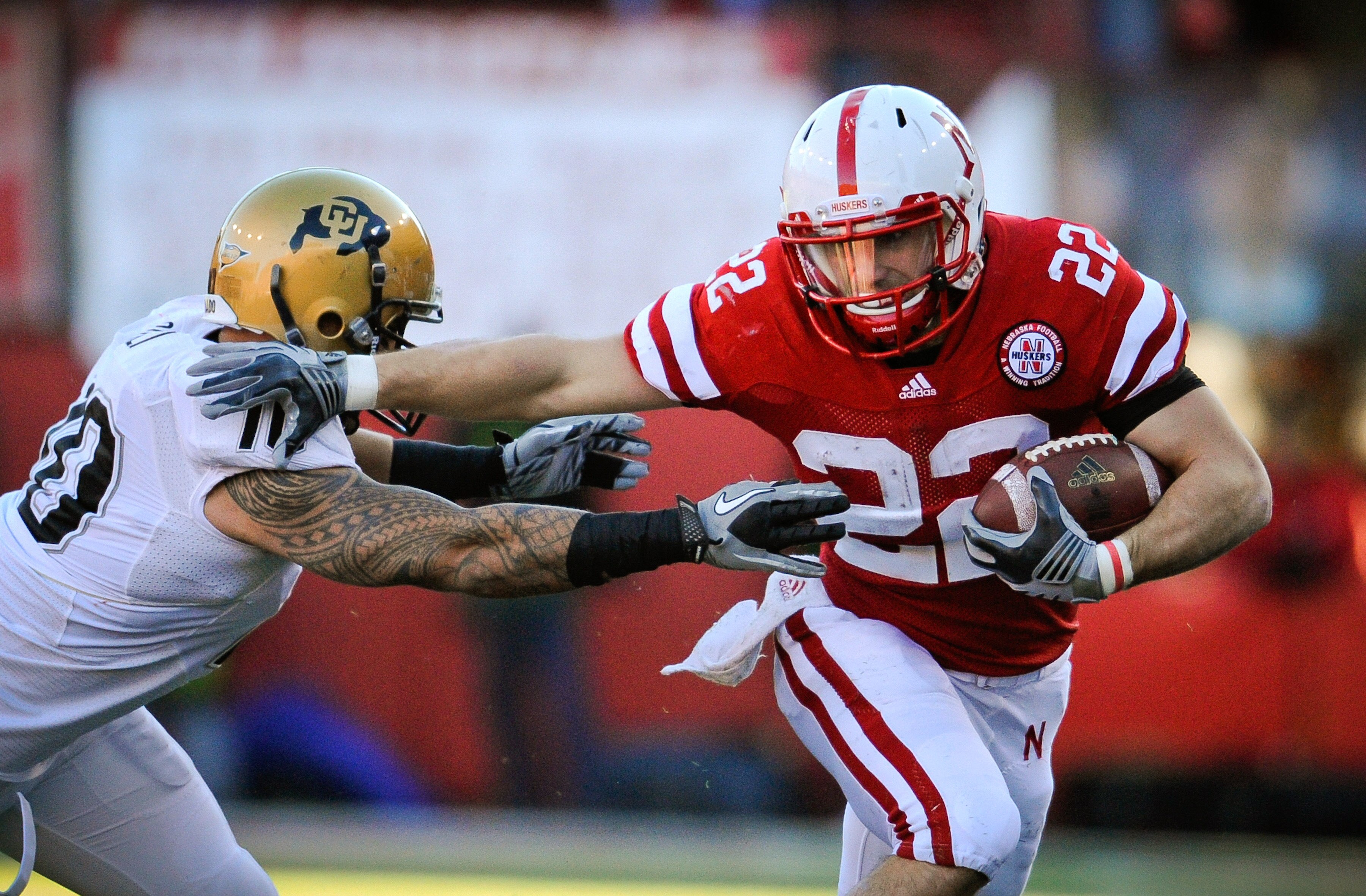 LINCOLN, NE - NOVEMBER 26: Rex Burkhead #22 of the Nebraska Cornhuskers runs past Michael Sipili #10 of the Colorado Buffaloes during the first half of their game at Memorial Stadium on November 26, 2010 in Lincoln, Nebraska.  (Photo by Eric Francis/Getty