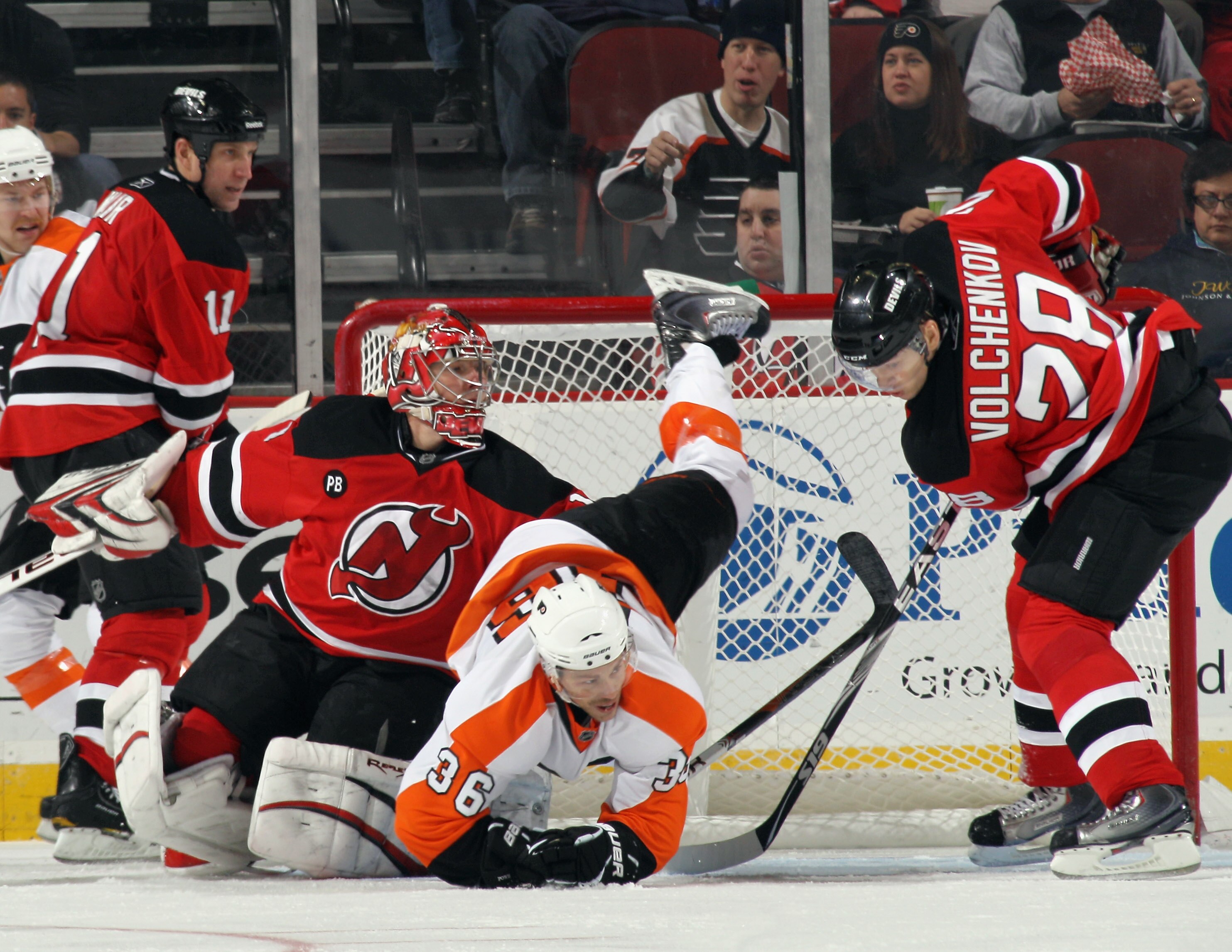 NEWARK, NJ - NOVEMBER 27: Darroll Powe #36 of the Philadelphia Flyers is upended as goaltender Johan Hedberg #1 and Anton Volchenkov #28 of the New Jersey Devils defend the net at the Prudential Center on November 27, 2010 in Newark, New Jersey.  (Photo b