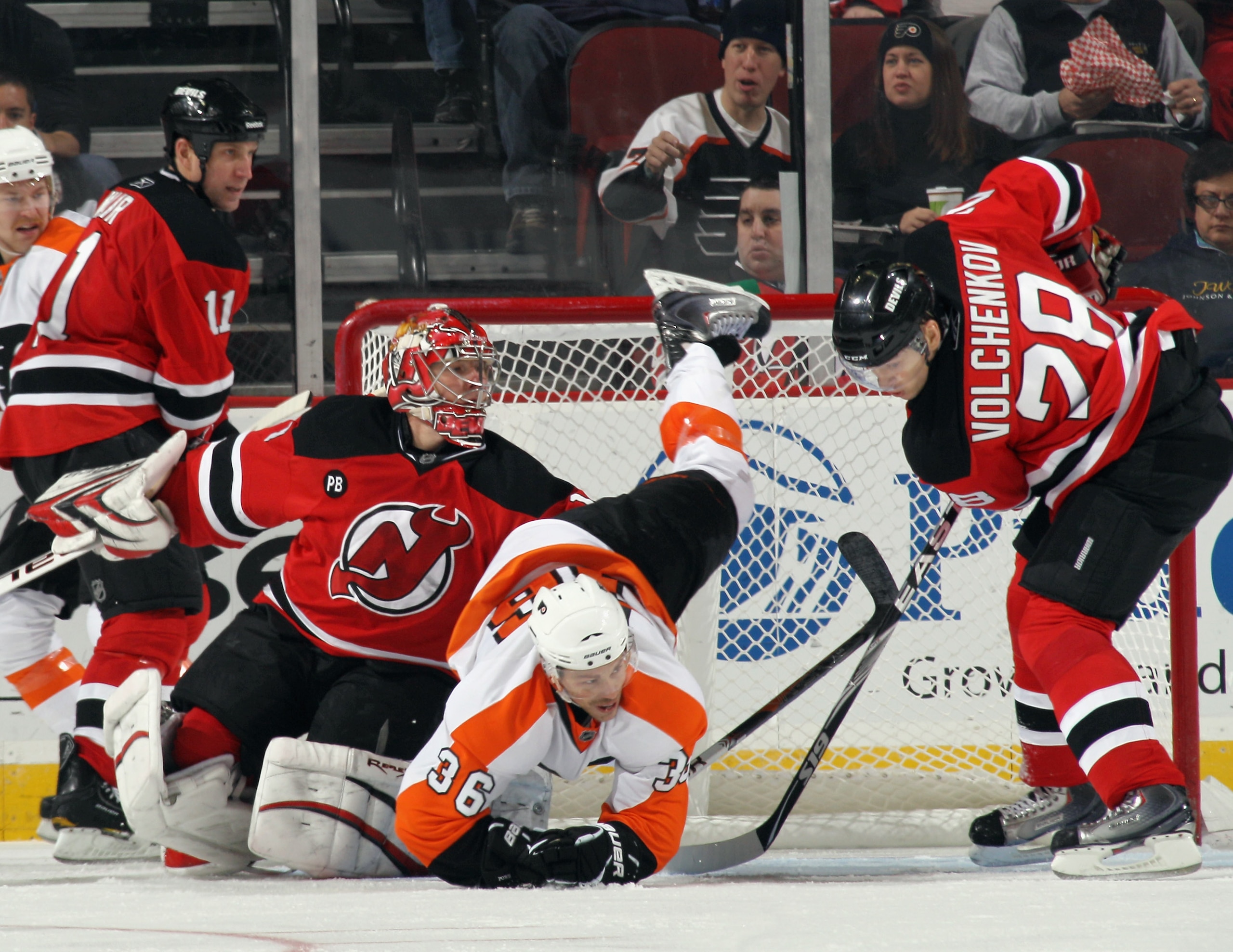 NEWARK, NJ - NOVEMBER 27: Darroll Powe #36 of the Philadelphia Flyers is upended as goaltender Johan Hedberg #1 and Anton Volchenkov #28 of the New Jersey Devils defend the net at the Prudential Center on November 27, 2010 in Newark, New Jersey.  (Photo b