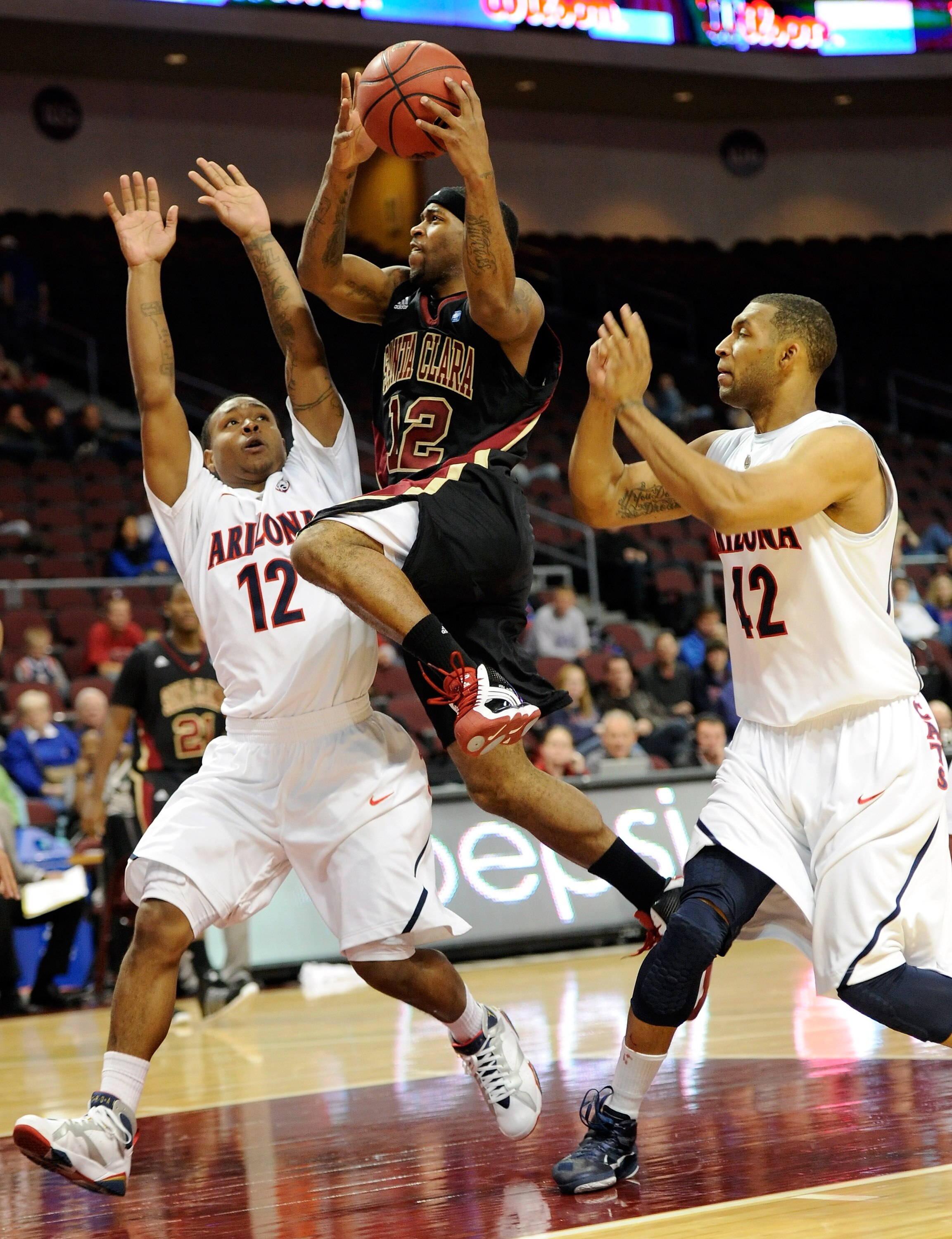 LAS VEGAS - NOVEMBER 26:   Robert Smith #12 of the Santa Clara Broncos drives between Lamont Jones #12 and Jamelle Horne #42 of the Arizona Wildcats during the third round of the Las Vegas Invitational at The Orleans Arena November 26, 2010 in Las Vegas,