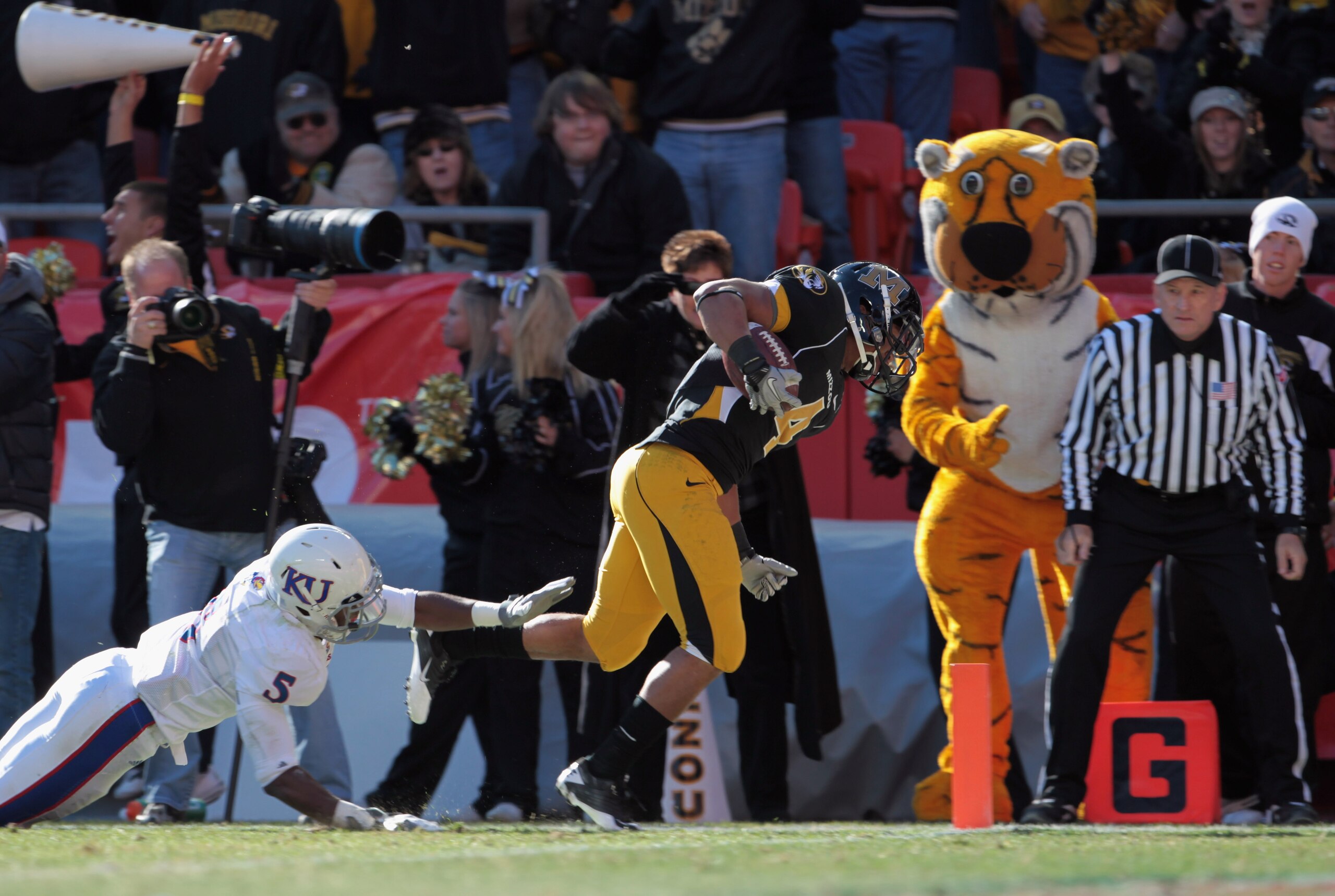 KANSAS CITY, MO - NOVEMBER 27:  Kendial Lawrence #4 of the Missouri Tigers carries the ball across the goal line for a touchdown as Greg Brown #5 of the Kansas Jayhawks defends during the game on November 27, 2010 at Arrowhead Stadium in Kansas City, Miss